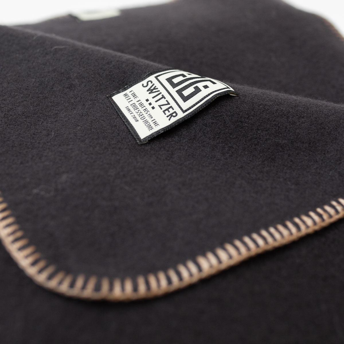 Die Decke Classic in Bark (aubergine/braun) ist eine maßgeschneiderte Decke, die exklusiv von JG SWITZER aus 100% Merinowolle hergestellt wird. Der Blankettstich wird in unserer Werkstatt in einem schönen Ecru-Ton hergestellt. Das Deckenstichgarn