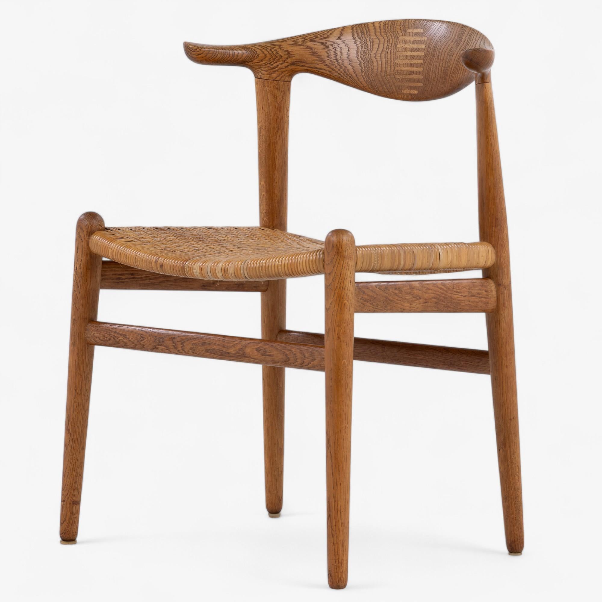 JH 505 - 'Kuhhorn-Stuhl' aus patinierter Eiche mit originalem Korbsitz. Der Entwurf stammt aus dem Jahr 1952 von Hans J. Wegner. Hergestellt von Johannes Hansen.