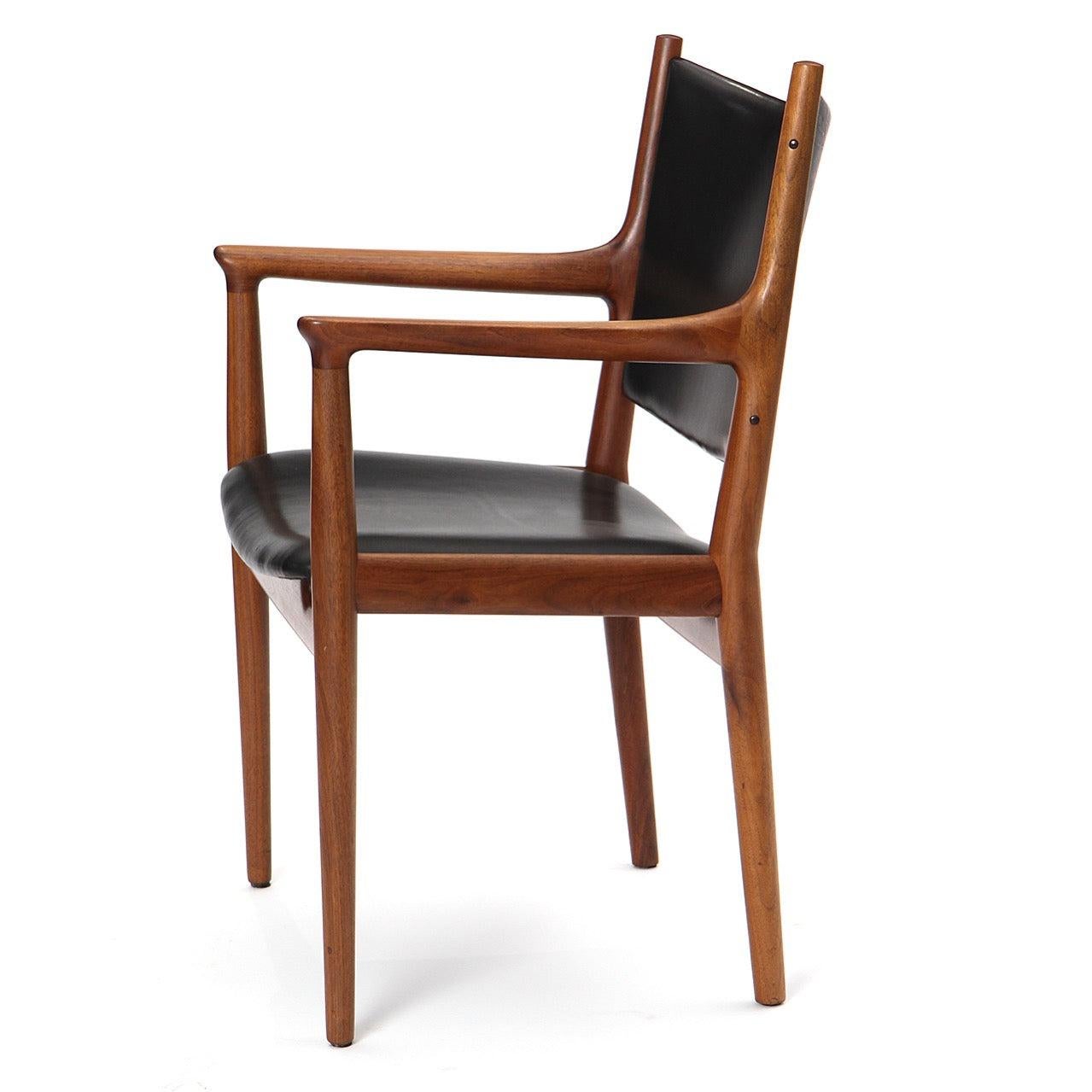 Un'elegante sedia da pranzo artigianale con struttura in teak a vista e rivestimento in pelle.