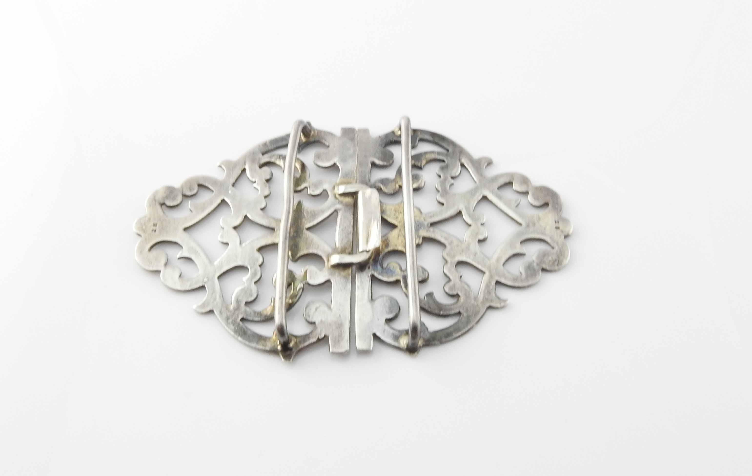 Sterling silver nurses buckle by JHL London.

Marked: JHL Lion (sterling silver), leopard (London city mark), O (1969 year mark) on one side of buckle, lion and leopard mark on other side of buckle. Also marked 28 on both sides of the back of the