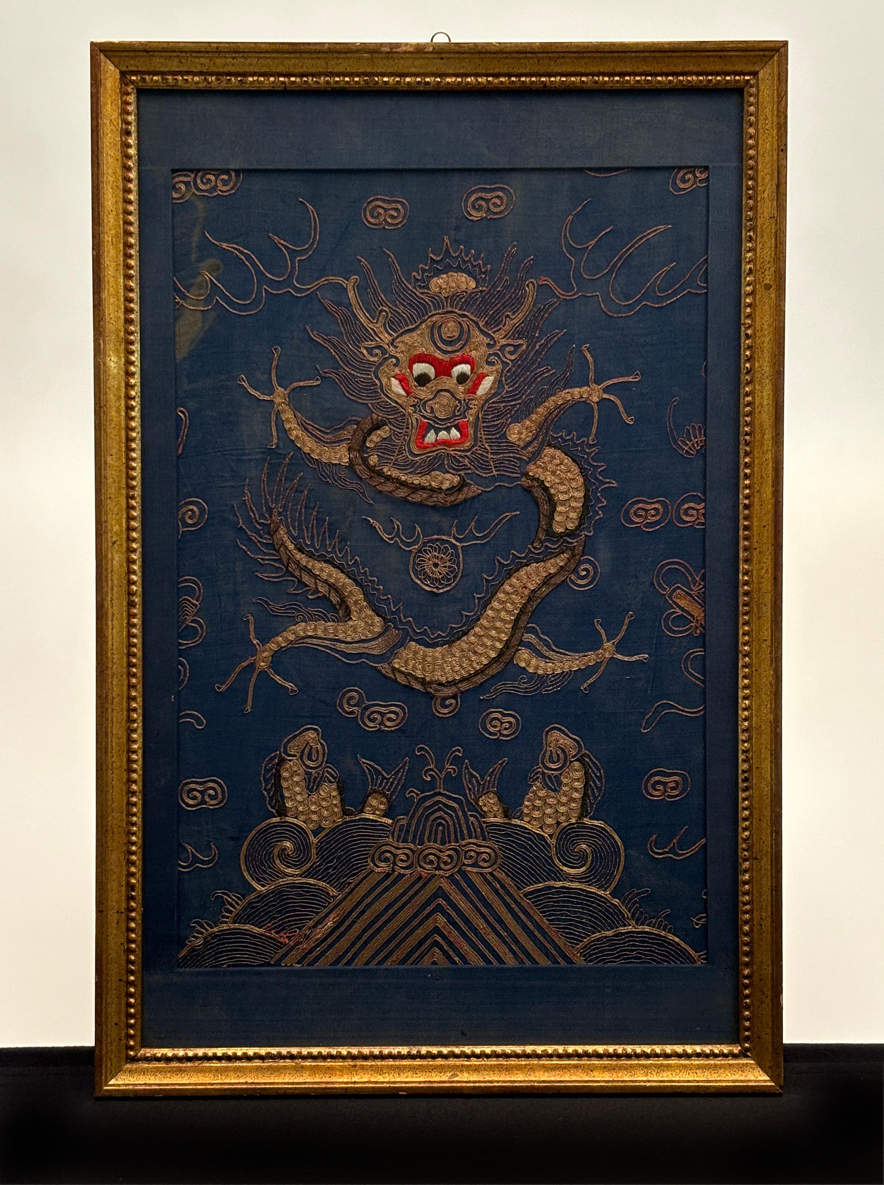 This pair of gold gilt framed 18th century four-clawed dragons are quite stunning in both artistic composition and technical execution. Created c. 1796, these elegant pieces were masterfully created and anchored to a deep teal blue silk base with