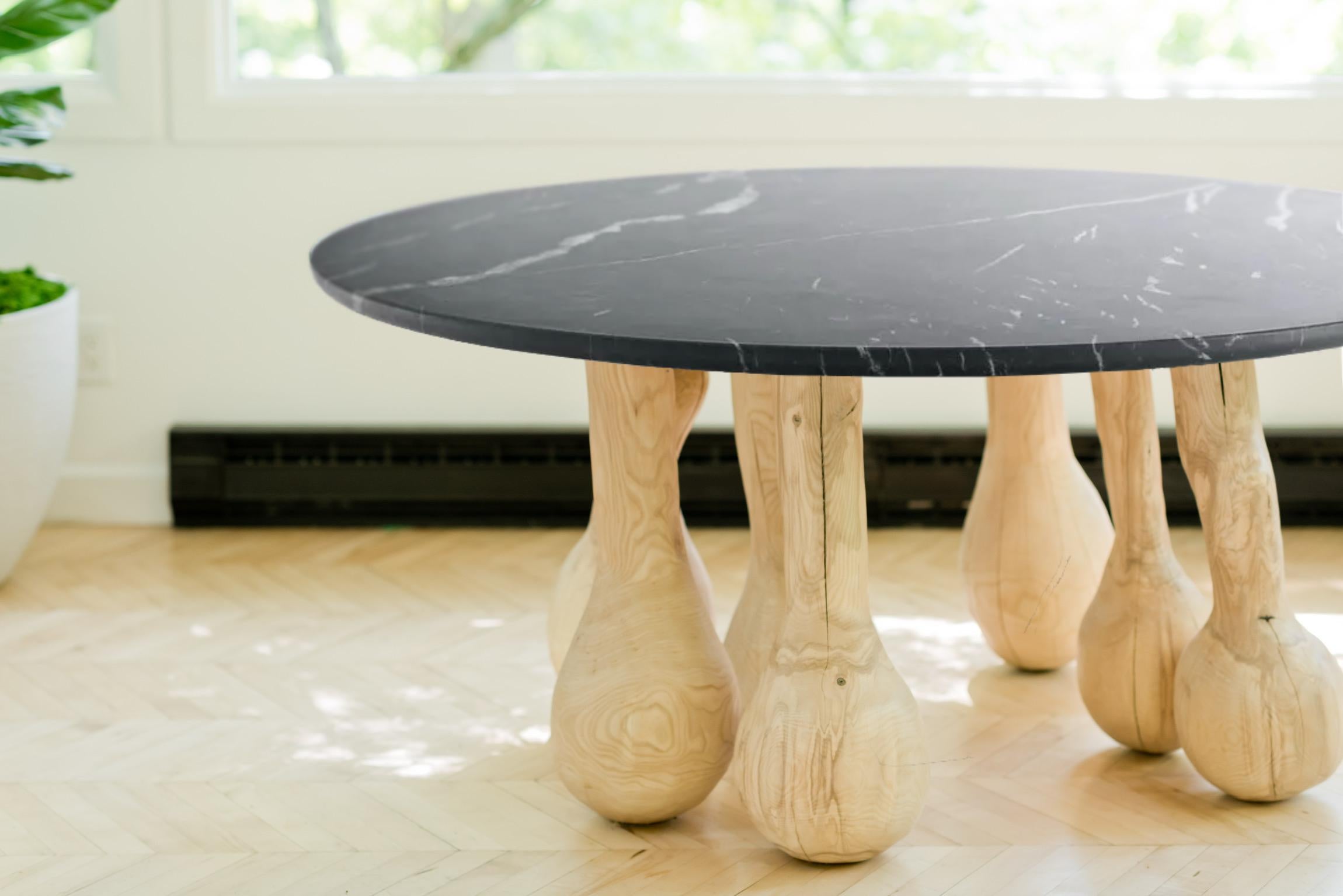 Carved from wood that whispers tales of its earthy origins, the table stands on legs shaped like droplets of time - bulbous and full of gravity, yet utterly balanced. 

In this work, the artist reimagines the traditional dining table as a living,
