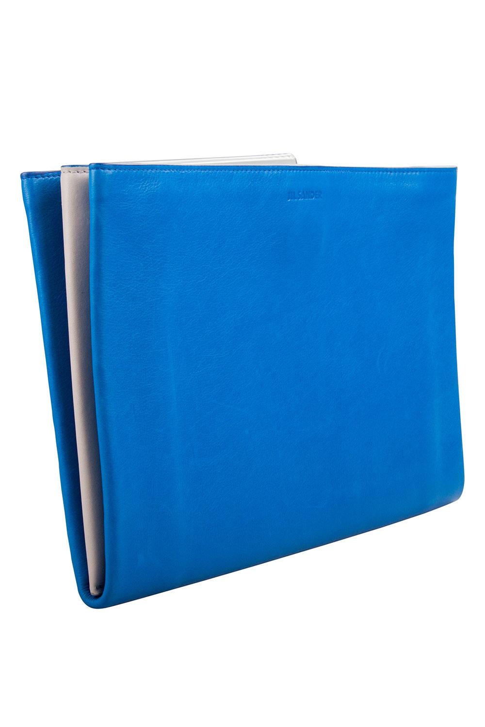 Portez cette pochette bleue et blanche de la maison Jil Sander. L'accessoire en cuir est doté d'une fermeture supérieure à boutons-pression et d'un intérieur approprié divisé en compartiments pour votre confort. Arborant le logo de la marque sur le