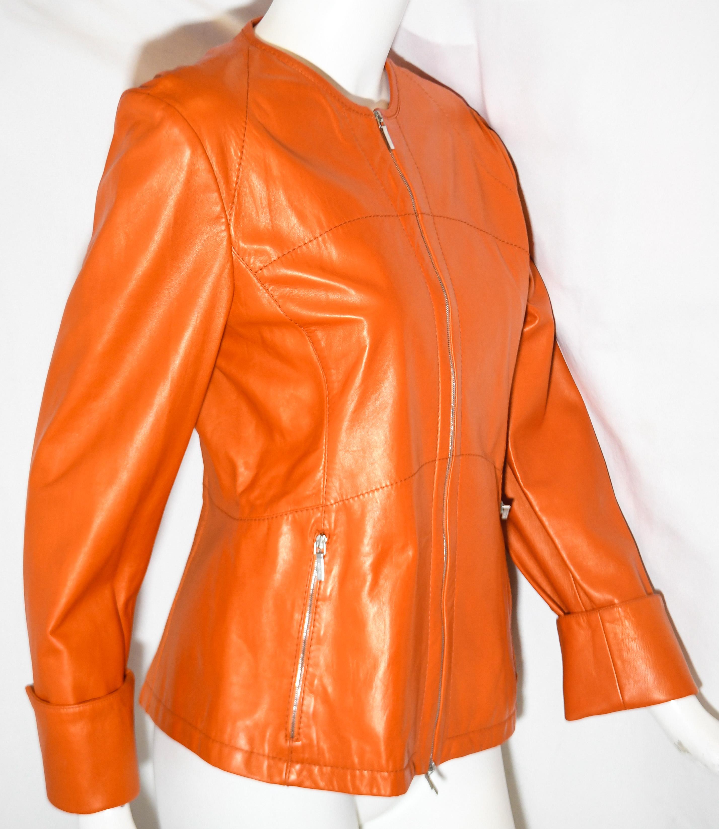 Jil Sander orange leather jacket is fit to the body and includes one silver tone front zipper for closure and two silver tone side zippers one for each pocket.  This jacket is expertly created in Italy.  Jacket is lined in orange fabric.  This round