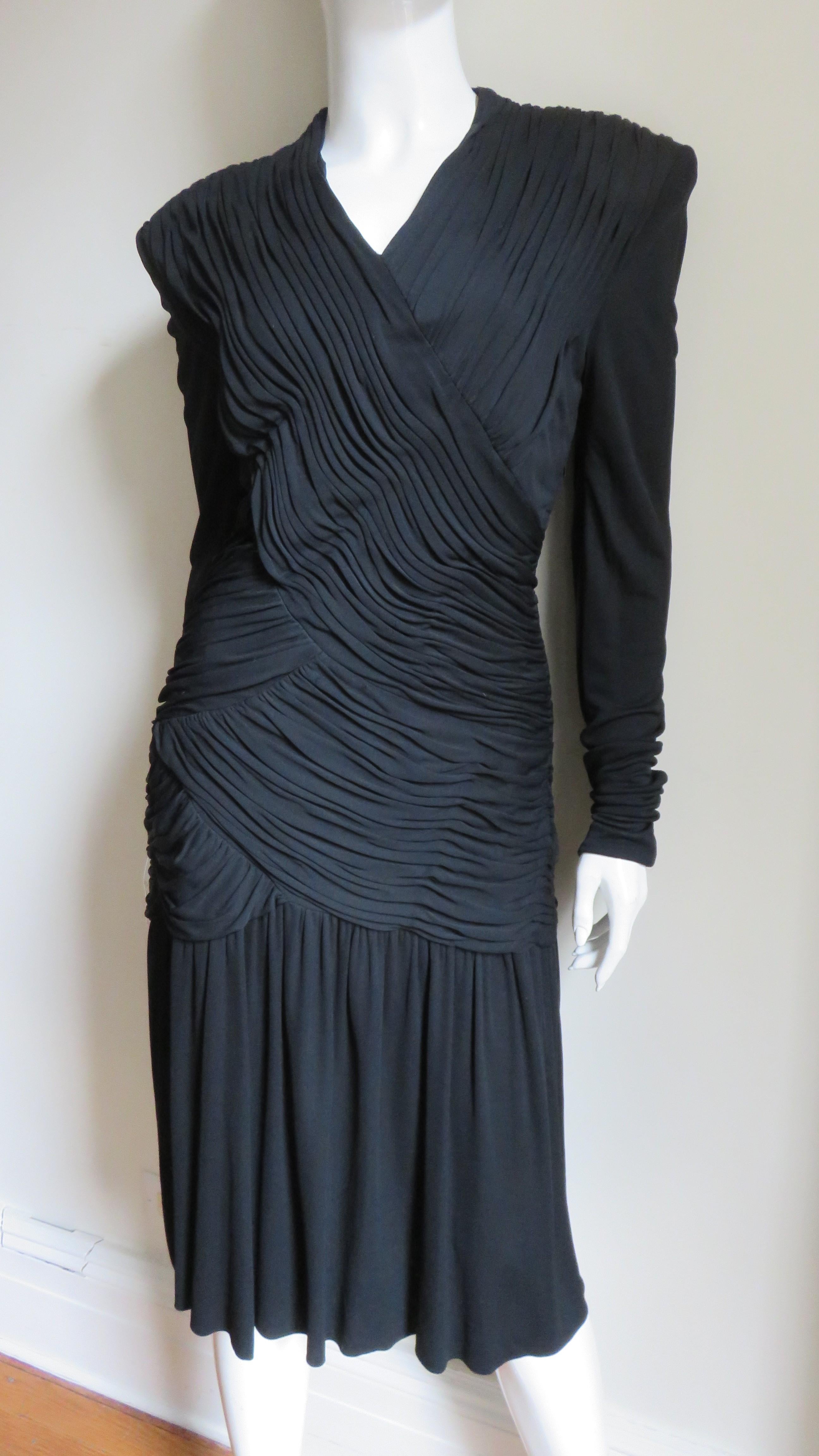 Un fabuloso vestido fino de punto de seda negro de Jil Sander. Tiene escote en V, mangas largas, hombreras y paneles fruncidos en varios ángulos por delante y por detrás, desde los hombros hasta las caderas. Está totalmente forrado y tiene una