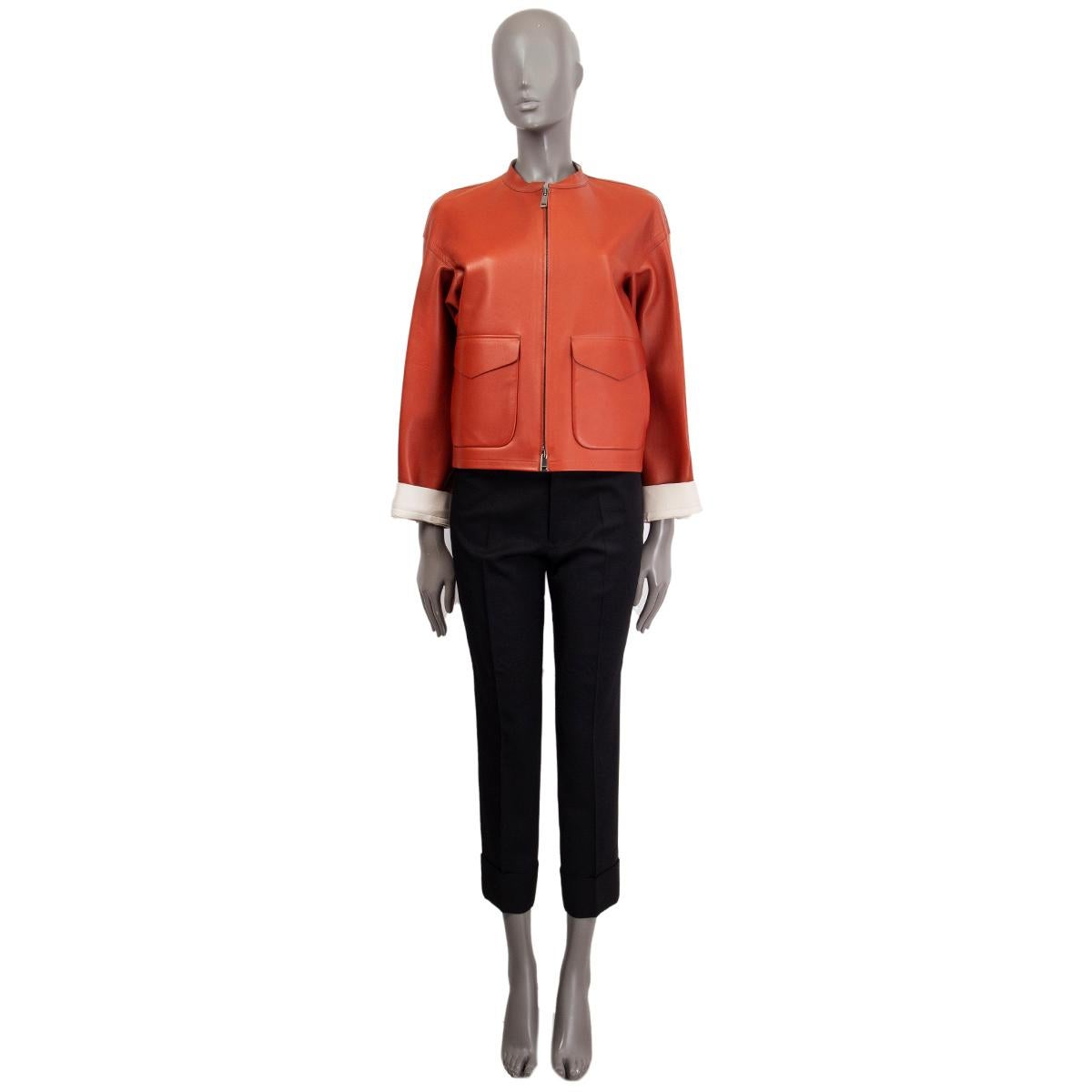 100% authentic Jil Sander bat sleeve short jacket in rust and off-white lambskin featuring two flap pockets and slit pockets at front. Opens with a zipper and is lined in off-white lambskin. Has been worn with some faint stains on the off-white part