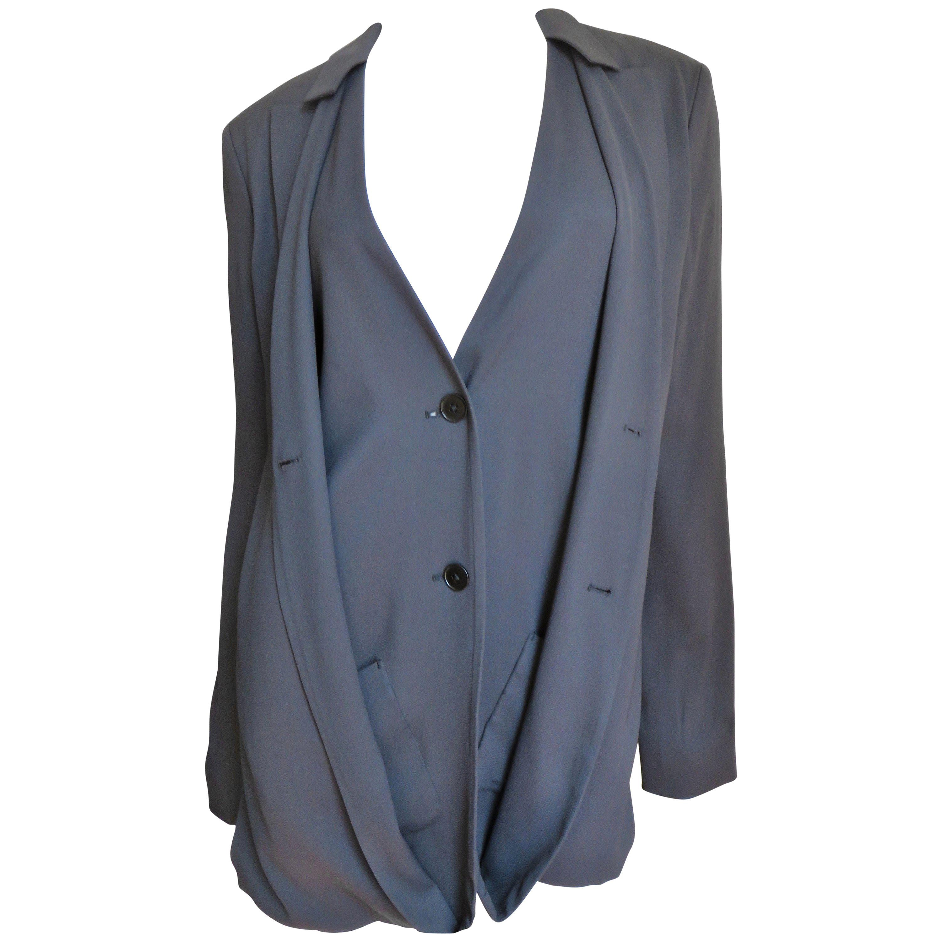 A gorgeous charcoal grey silk jacket from designer Jil Sander.  It has long sleeves and from the front when buttoned presents as a blazer.  Unbutton and under is a vest which has 2 grey buttons closing, patch pockets and the back is cropped to the