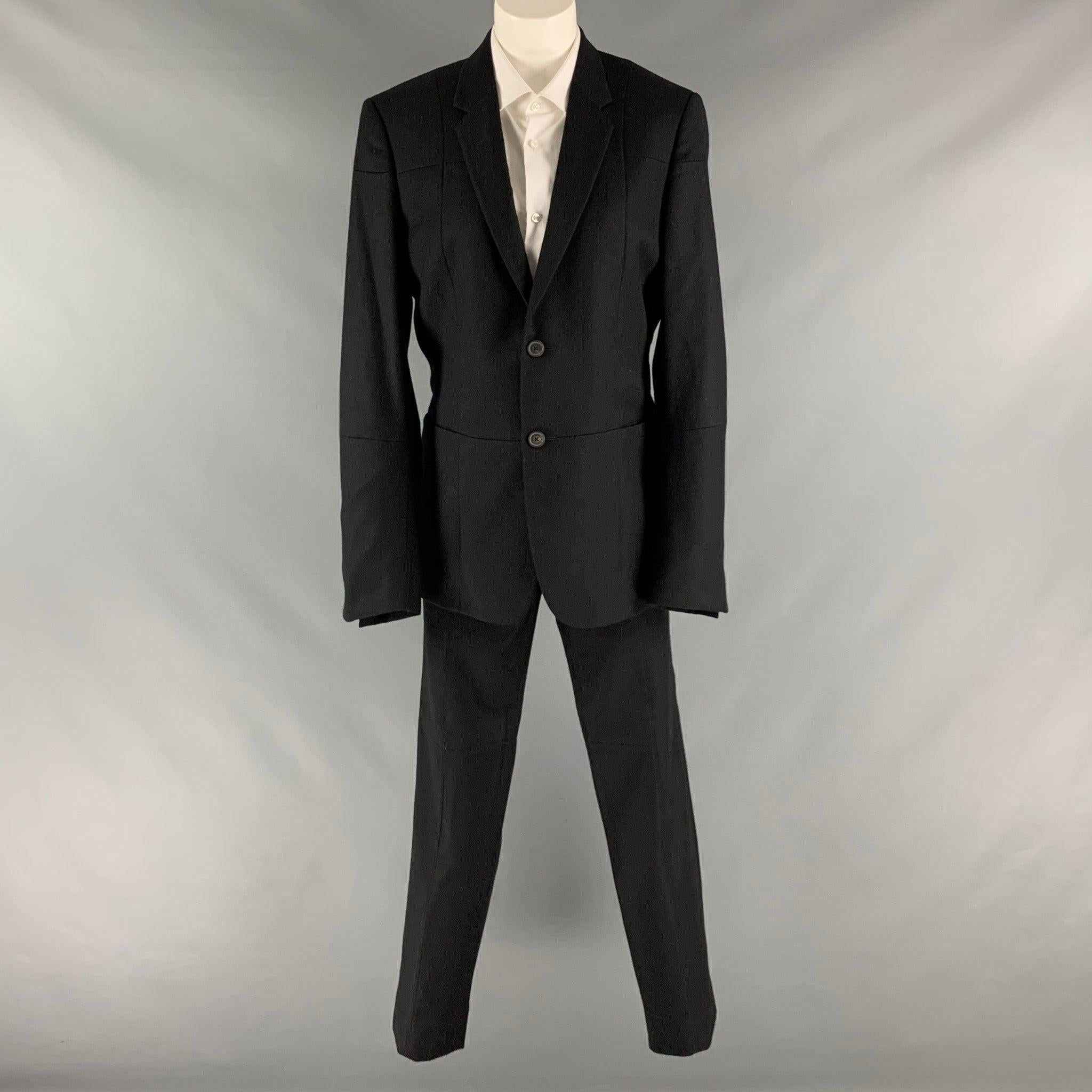 JIL SANDER suit comes in a black wool warm material and includes a single breasted, double button sport coat with a notch lapel, patchwork details and matching flat front trousers. Made in Italy.Very Good Pre-Owned Condition. Minor mark at back.