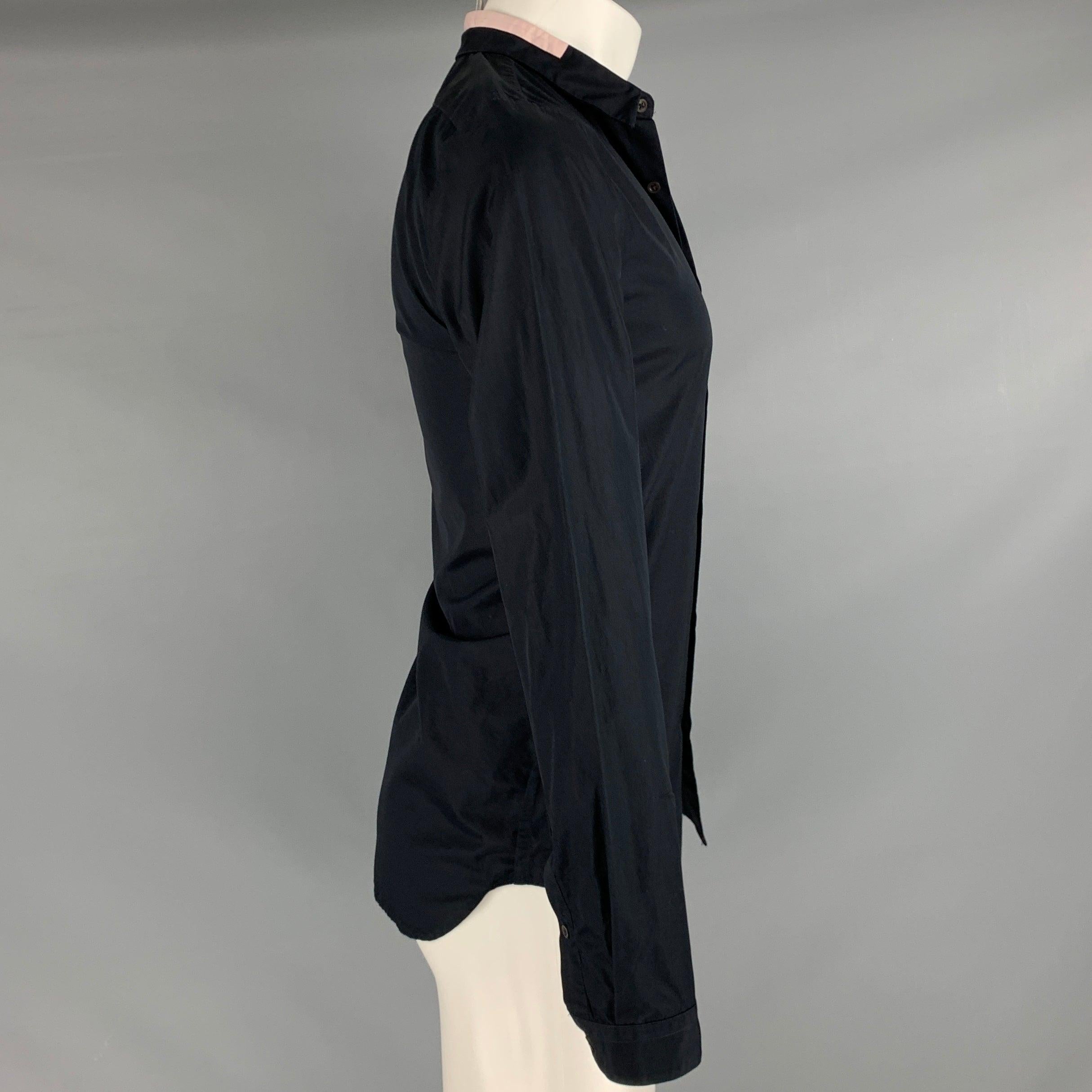 Chemise à manches longues JIL SANDER
dans un tissu de coton noir, avec un détail de col étalé rose, des coutures inversées sur les côtés et sur les manches, et une fermeture à boutons. Fabriqué en Italie. Très bon état. Marque sur le col, étiquettes