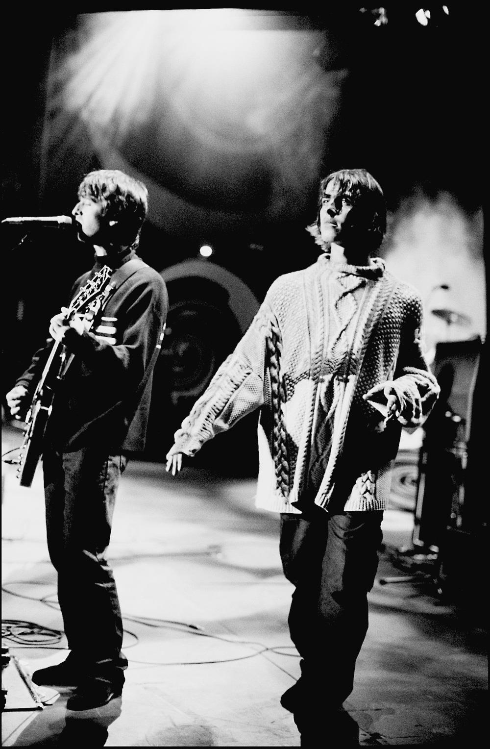 Tirage signé, en édition limitée, d'Oasis, Liam et Noel Gallagher par Jill Furmanovsky. Pris sur scène à Knebworth Park lors de leurs concerts emblématiques en août 1996.

Noel Gallagher parle du choix vestimentaire de Liam ce jour-là : "Porter le