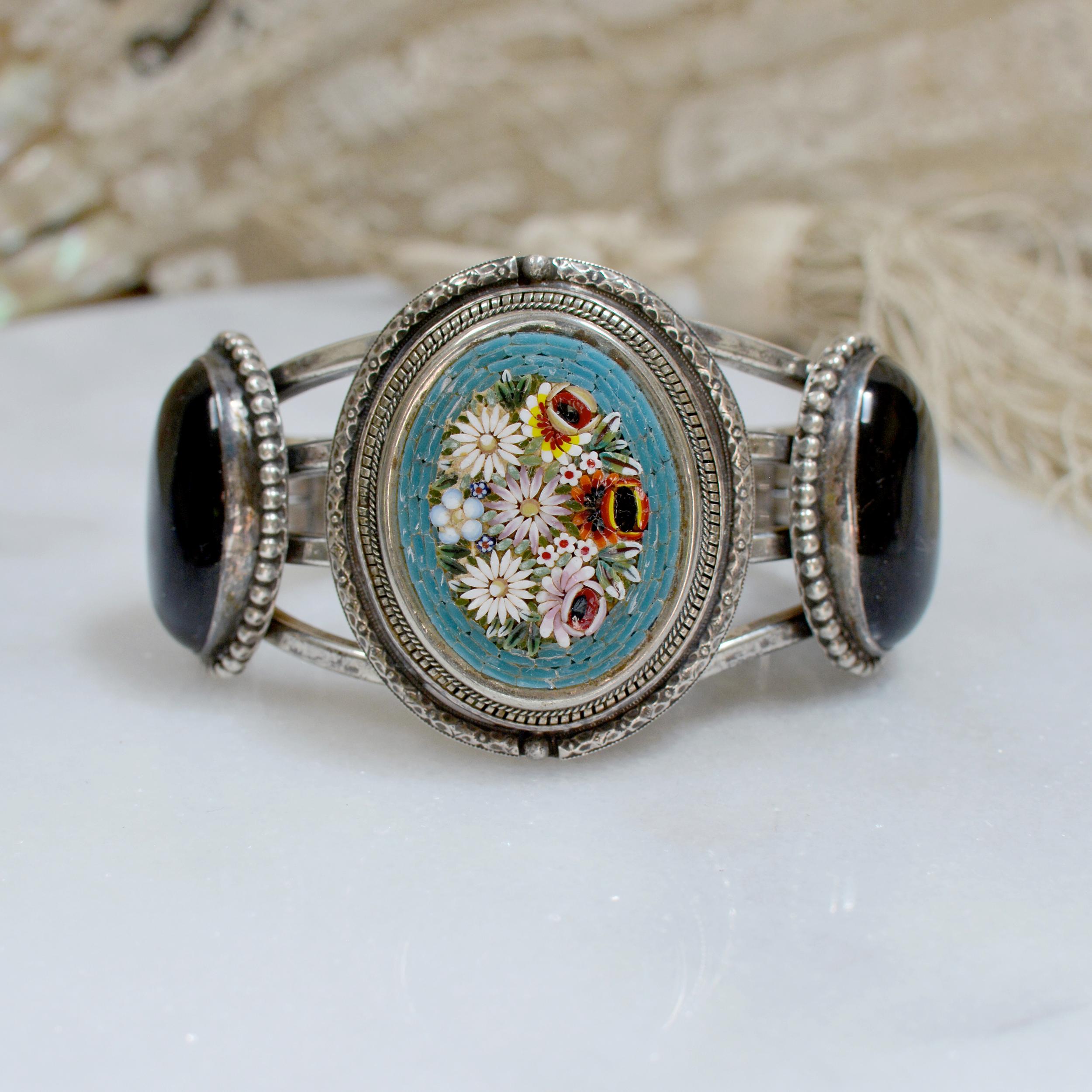 This bold one of a kind Sterling Silver cuff bracelet features an early twentieth century antique Venetian tesserae micro-mosaic floral bouquet panel with an exquisitely engraved sterling frame having a beaded inner edge around the mosaic. Accenting