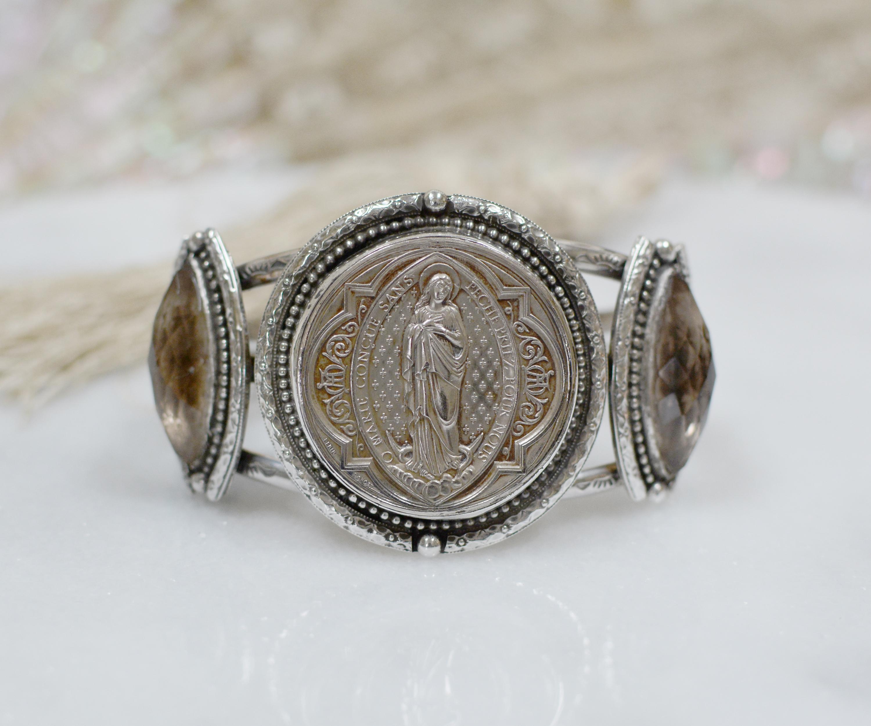 This one of a kind sterling silver Jill Garber cuff bracelet features a fine original antique nineteenth century French Sacred Heart Medal depicting Saint Mary, by engraver Ludovic Penin (1830 - 1868). This master French engraver was accorded the