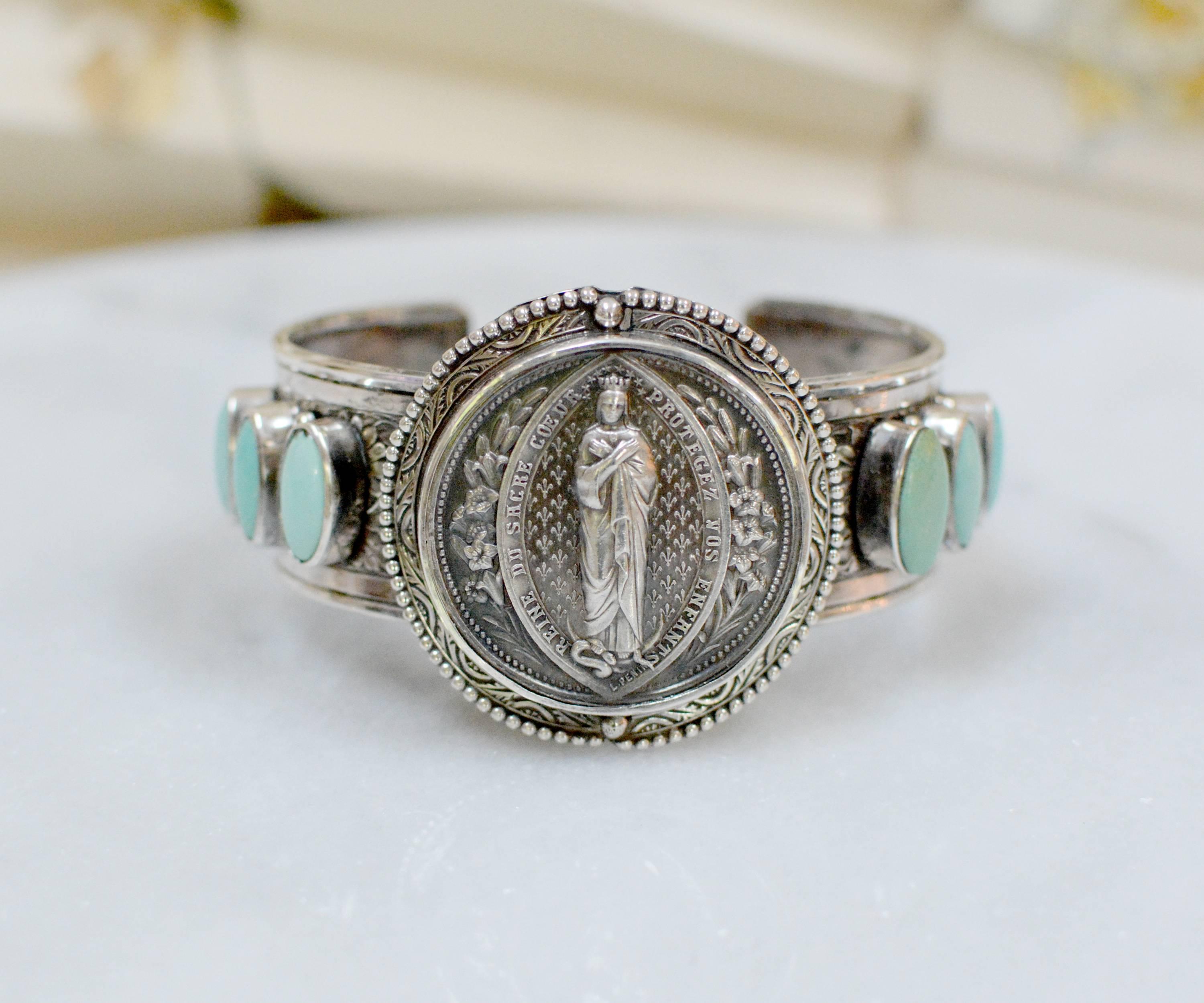 This one of a kind sterling silver cuff bracelet features a very fine, original antique nineteenth century French Sacred Heart Medal gloriously framed with engraving and silver beading. Accenting either side are six 6 x 9 mm robin's egg blue natural