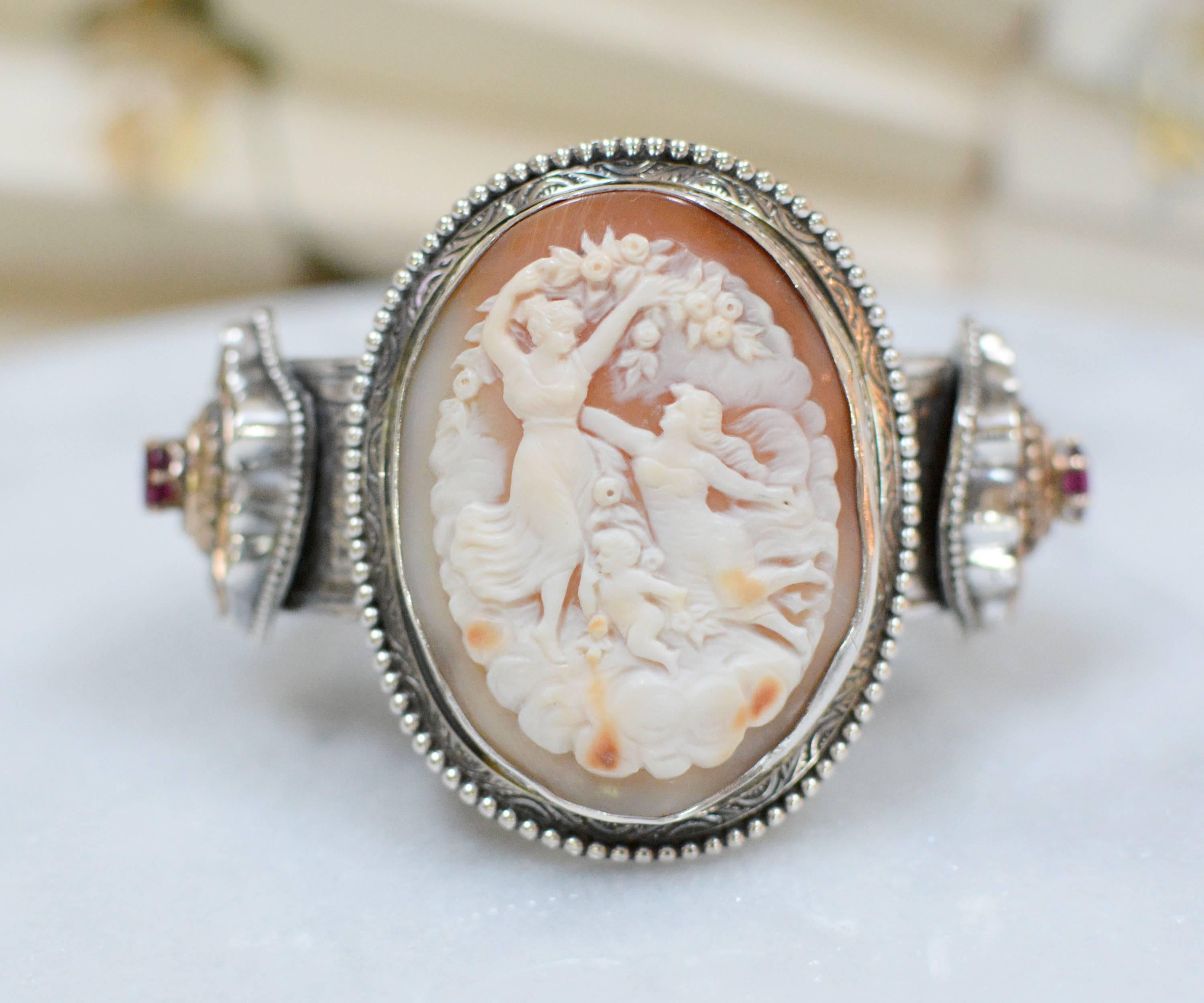 This one of a kind sterling silver cuff bracelet features a museum quality nineteenth century  period cameo depicting two Goddesses with a cherub angel. On either side of this exquisite museum quality cameo are a pair of Victorian period gold