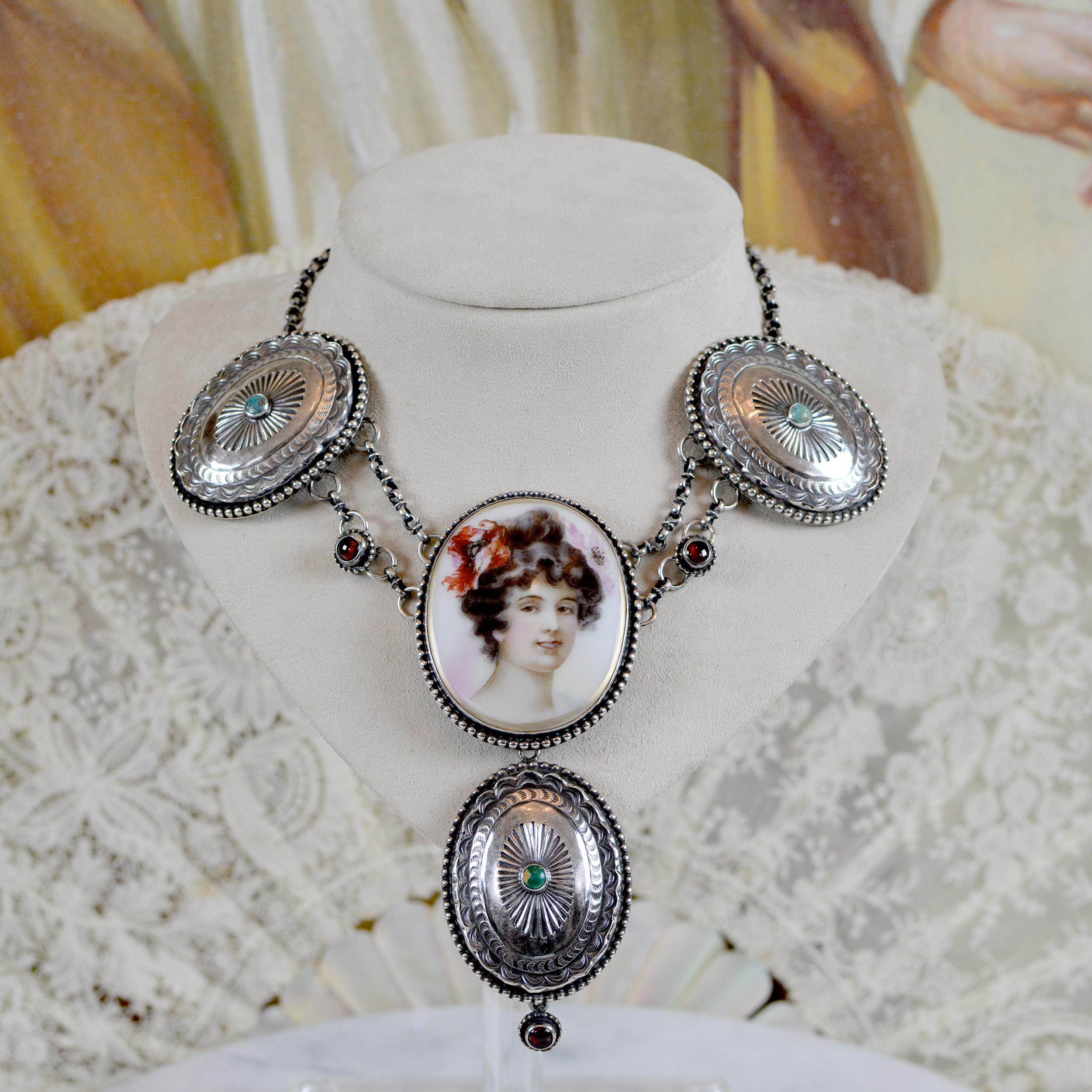 Questa collana a goccia con festoni, unica nel suo genere, presenta un antico ritratto in porcellana francese Art Nouveau risalente alla fine del XIX secolo. Con una perfetta fusione di epoche e culture - due audaci concho Navajo antichi stampati a