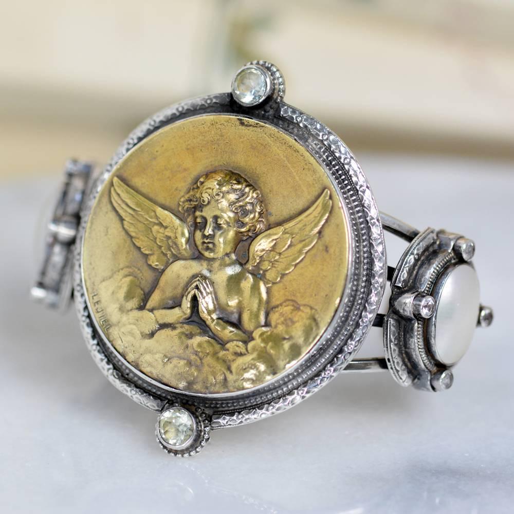 This one of a kind Sterling Silver cuff bracelet features a highly rare and collectible antique nineteenth century French medal depicting an angel in prayer signed LEJIEL. Accenting this wonderful piece are two 8mm faceted natural prasiolite. On