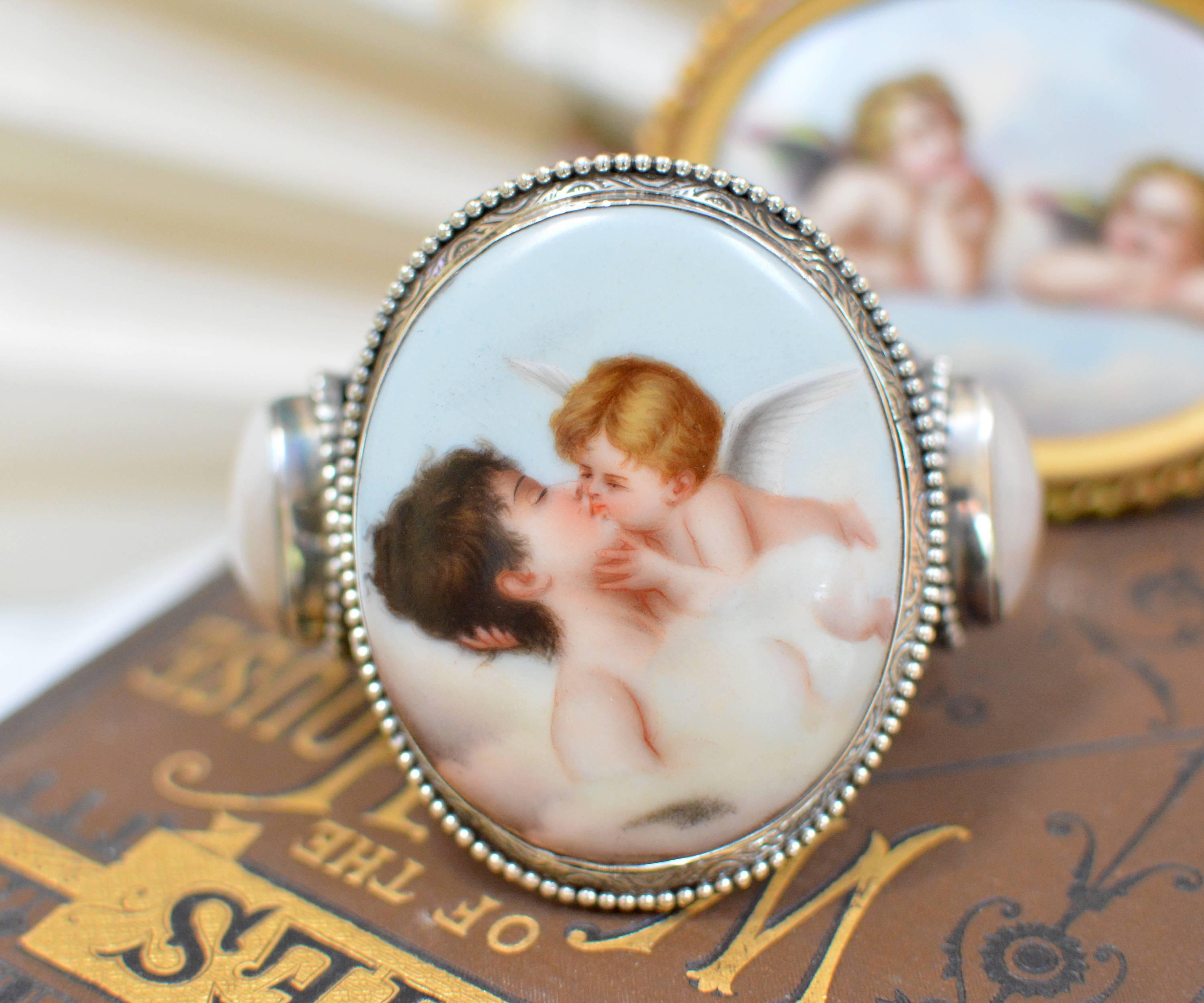 This exquisite Sterling Silver cuff bracelet features a  French porcelain portrait depicting Cupids Kiss. This exceptional image, painted after Antonio Canova's beloved sculpture - originally commissioned in 1787 resides proudly in a central court