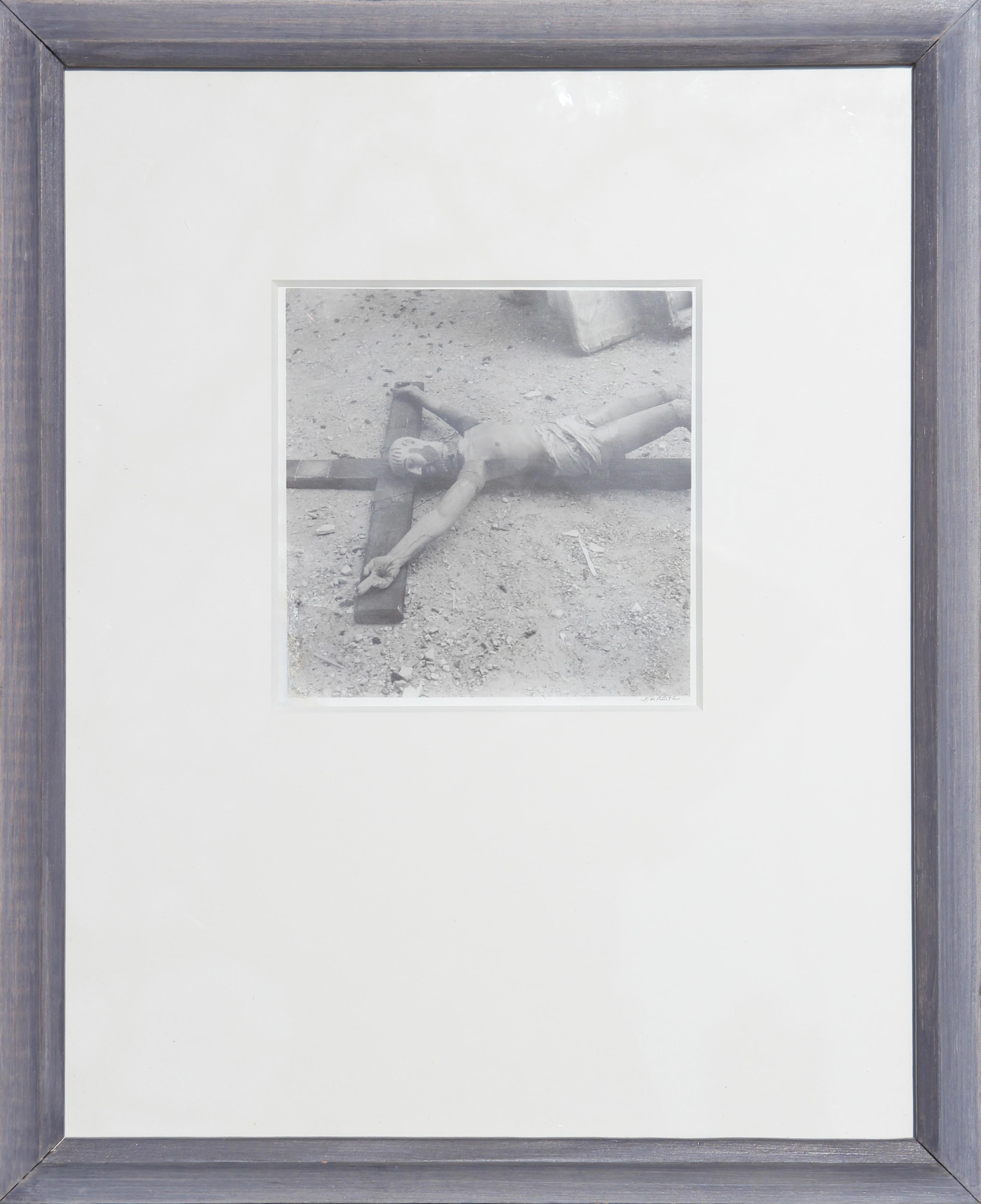 Schwarz-Weiß-Fotografie einer gefundenen Kruzifixskulptur auf dem Boden
