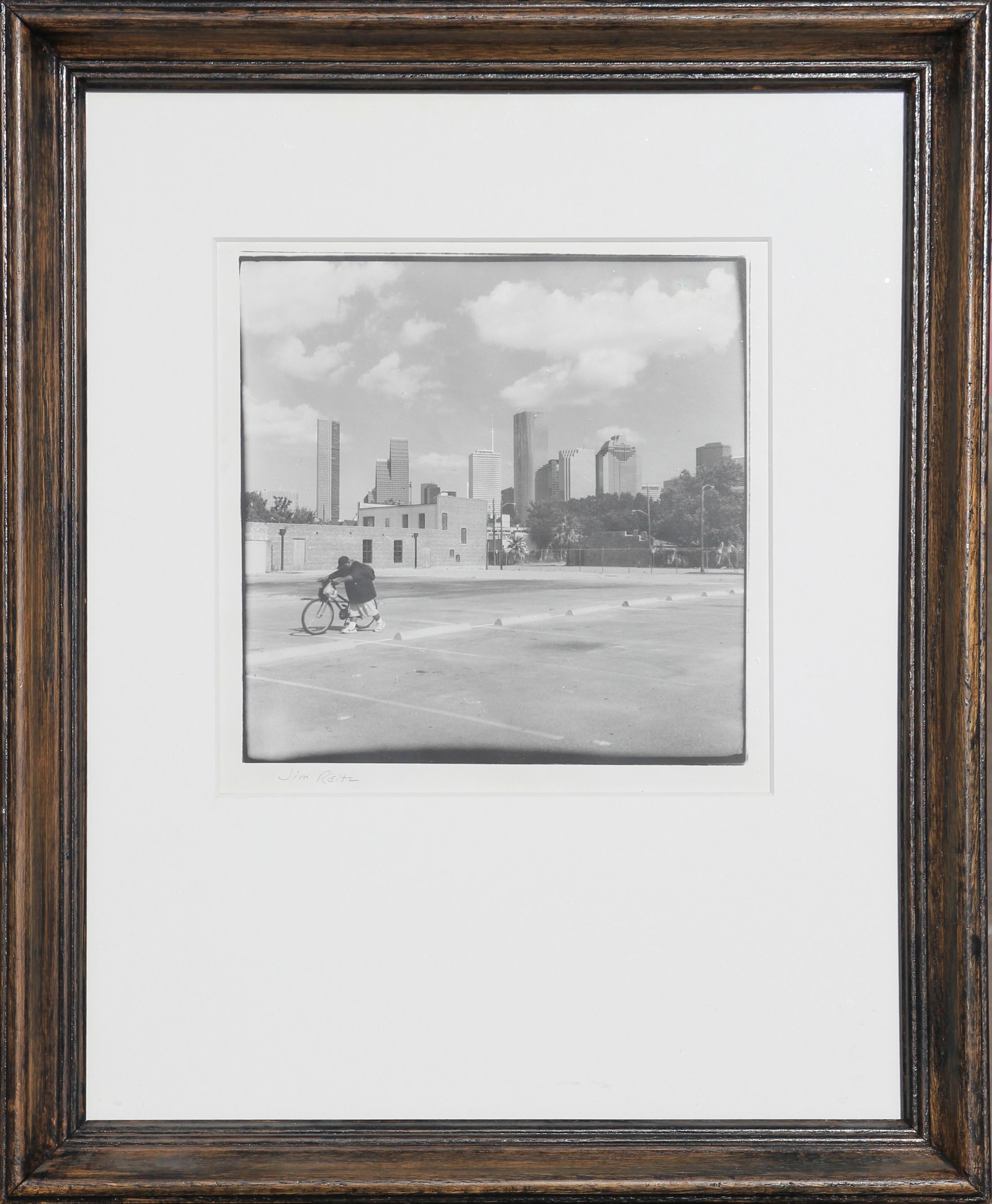 Schwarz-Weiß- Urban-Fotografie eines Mannes mit Fahrrad gegen die Skyline von Houston, TX