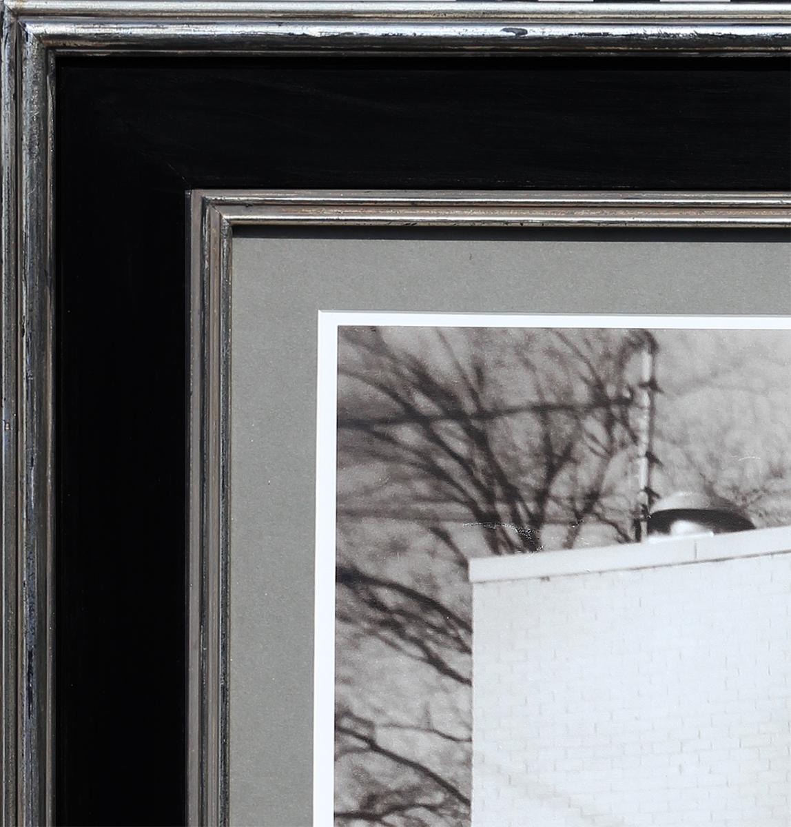 Photographie contemporaine en noir et blanc de l'artiste de Houston, TX, Jim Reitz. Cette photographie représente une scène de rue où un couple se tient près d'une peinture murale d'Obama. Cette fresque s'inspire de la célèbre affiche de Barack