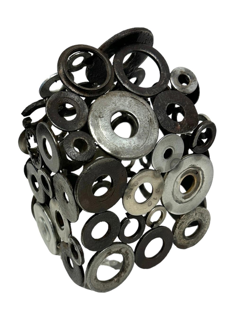 Jim Rose, known primarily for his steel furniture, was an avid collector and scoured salvage yards for unique, interesting items.  Here he has welded together various washers and cylindrical objects to form a house structure. The precision of the