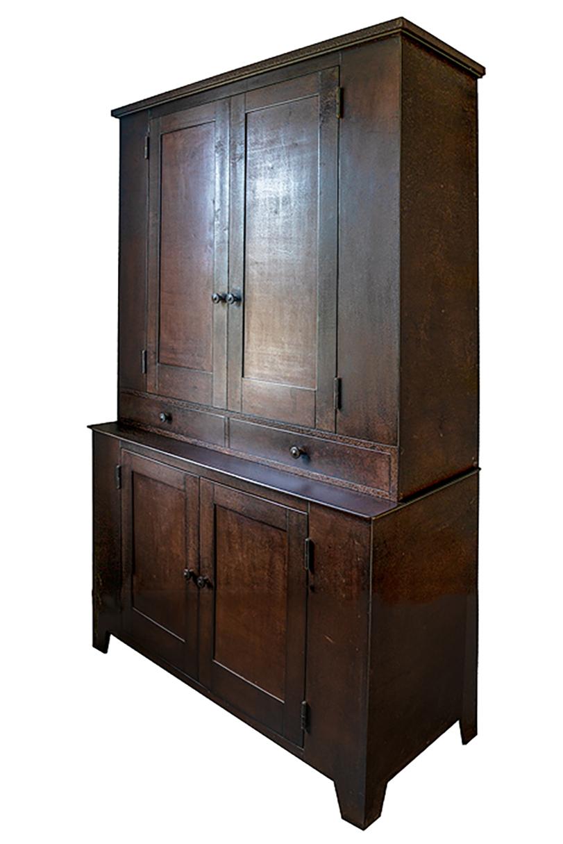 This impressive cupboard is inspired by Shaker furniture. A two door-two drawer cupboard stands atop another two door cupboard in this fully functioning steel cabinet by renowned furniture maker Jim Rose. With its timeless simplicity, this Shaker