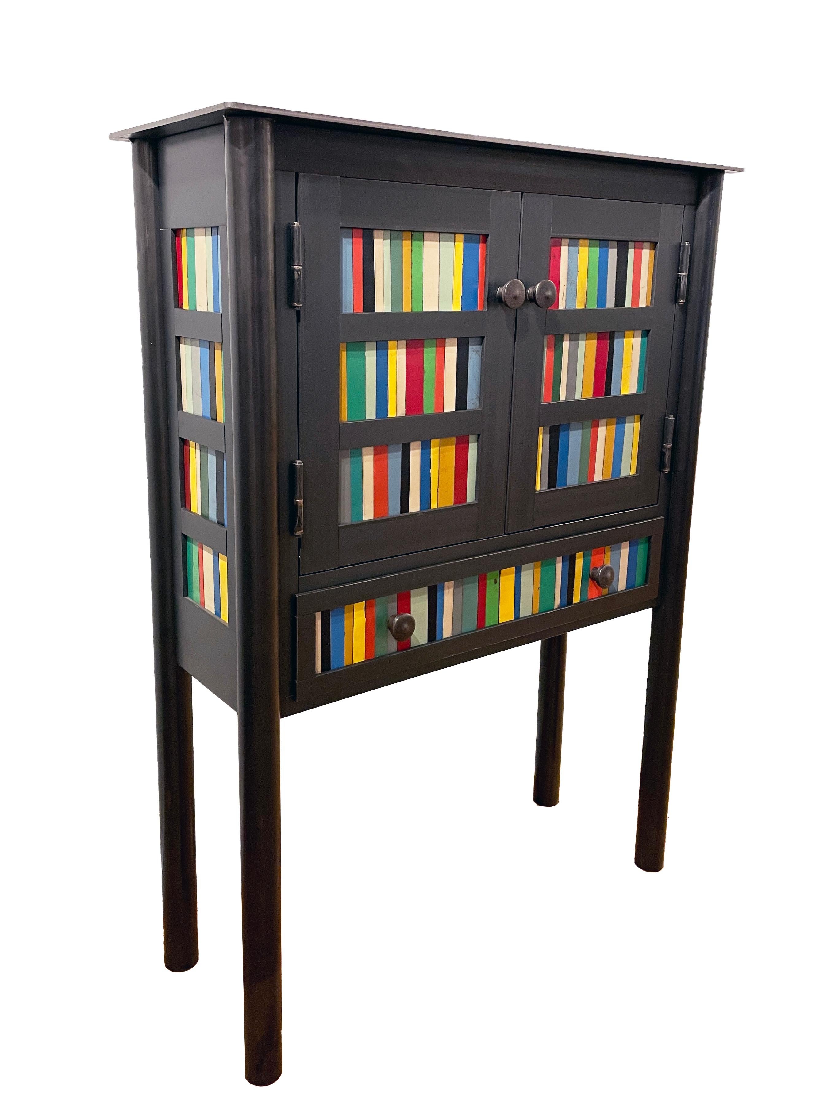 This modern cabinet is made from hot-rolled steel with the front and side panel designs based on the gees bend quilts. Each panel is unique with the use of painted steel strips that are salvaged. Its brightly colored pieces enhance the Industrial
