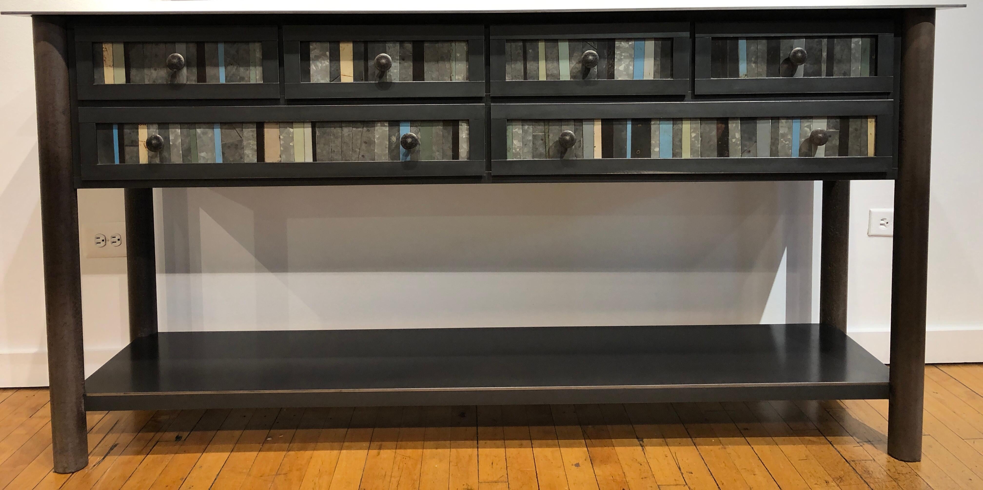 This modern six-drawer counter is made from hot roll blue steel with the front panel design based on the gees bend quilts. Each panel is unique with the use of galvanized rusted steel that is salvaged. Its rich grey, brown and beige tones enhance