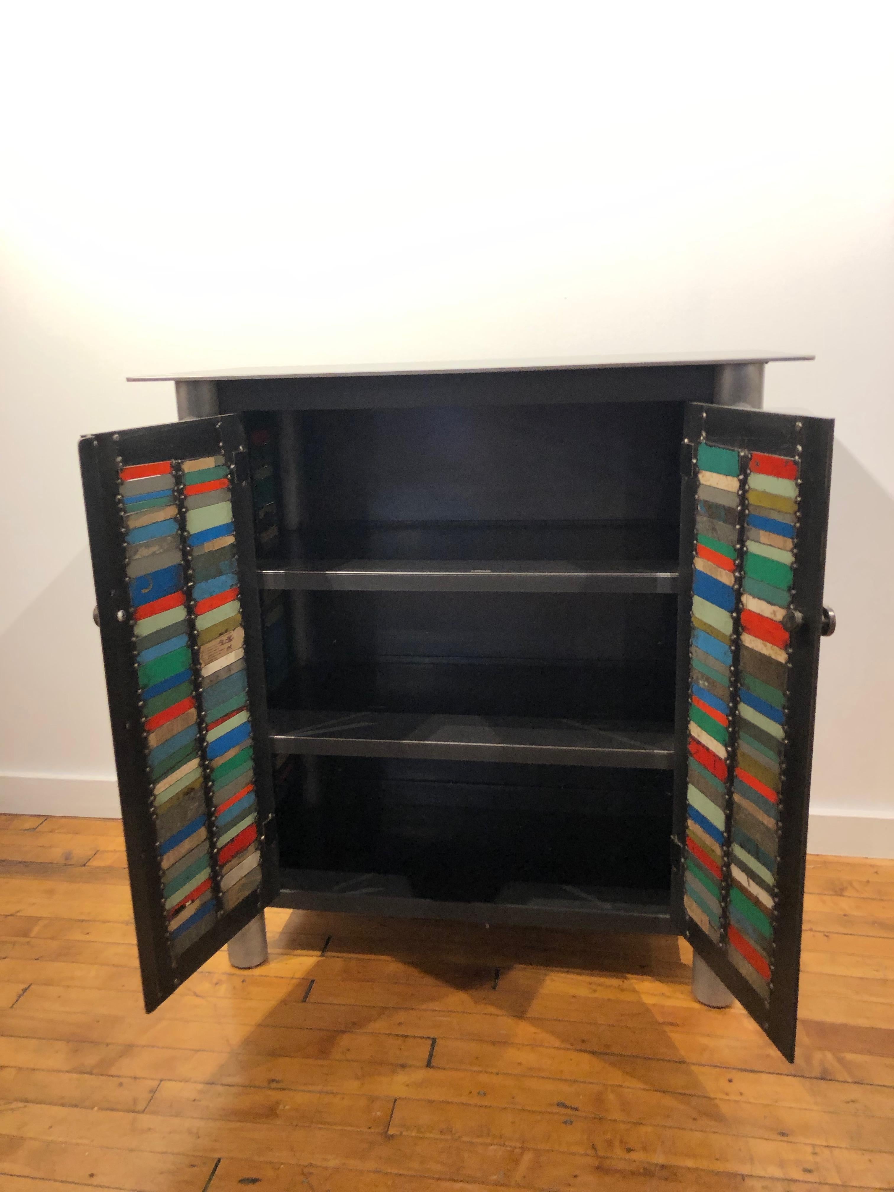 This is a totally functional two door cupboard. It is created from hot-rolled steel and found steel. The legs are made from salvaged pipe. The panels on the door fronts and sides are made from salvaged pieces of steel with the original paint and