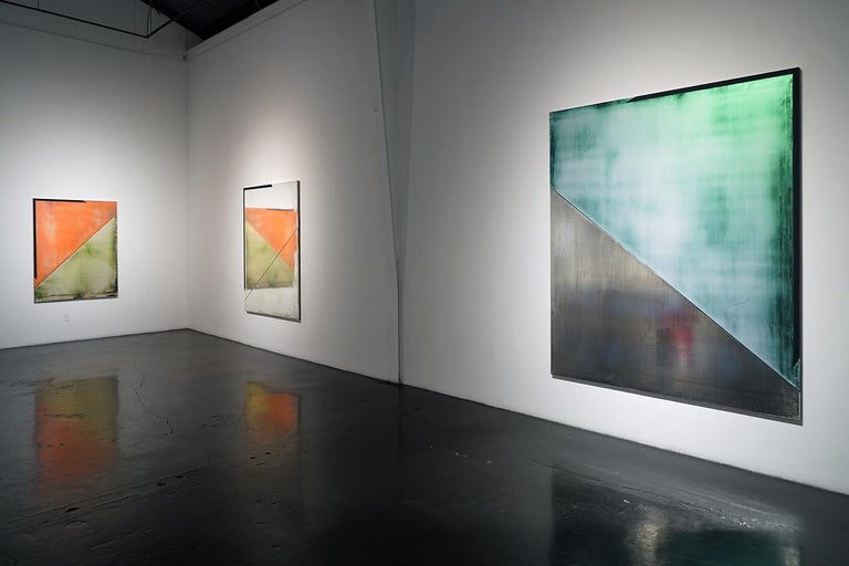 Like water, Gleason’s surfaces are quietly in motion, their iridescent paints subtly shifting hues as light plays across them. In each of the canvases, sharp diagonals bifurcate the compositions, providing dramatic structural rifts to these ethereal