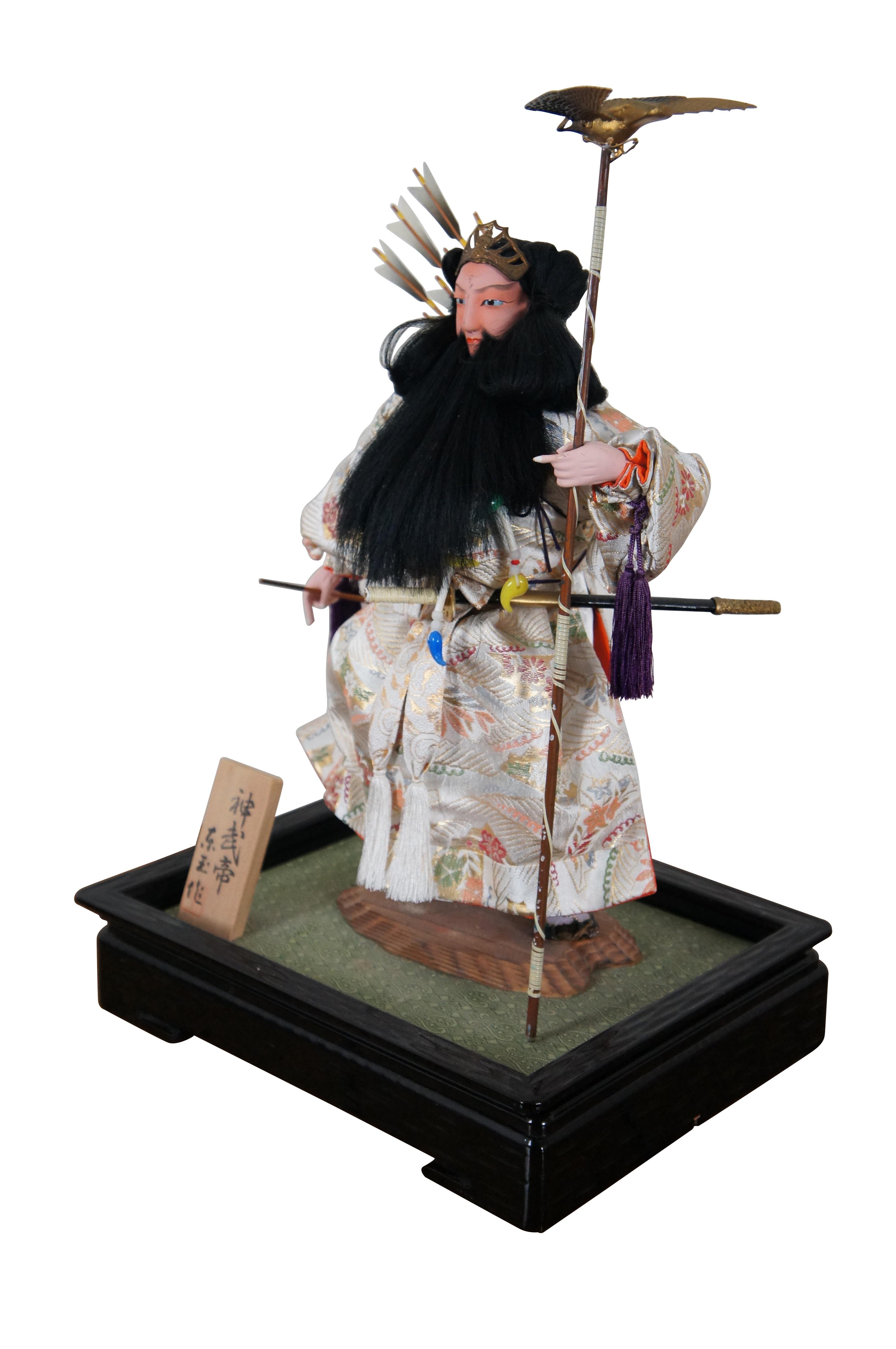 Vintage doll / figurine portraying Jinmu Tenno – Japan’s legendary first emperor. The doll is crafted with un-glazed porcelain / bisque head and hands, painted features and a lovely white silk robe. The Emperor wears a quiver of arrows on his back,