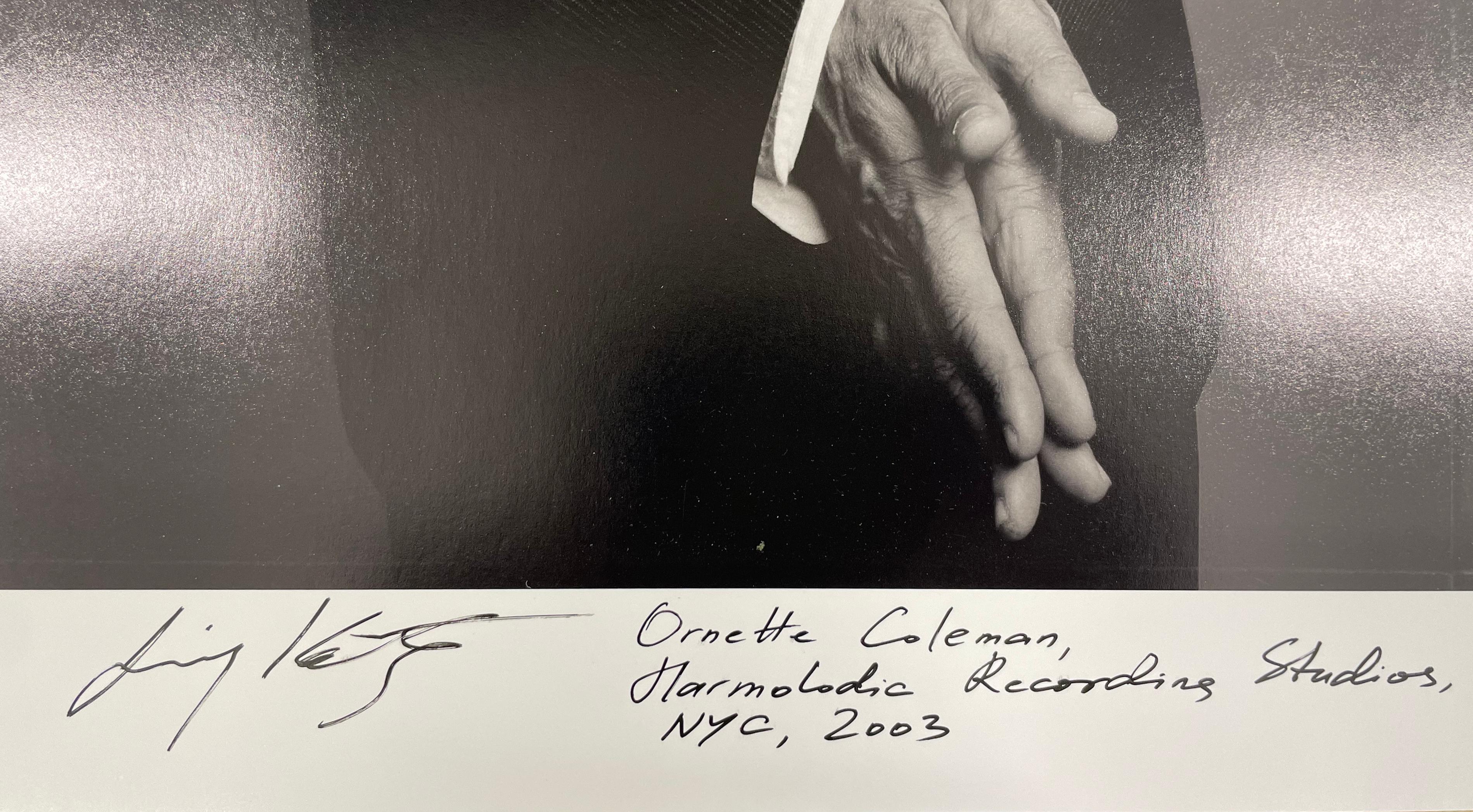 Ornette Coleman, Harmolodic Recording Studio, NYC ist ein Schwarz-Weiß-Porträt des amerikanischen Jazz-Saxophonisten, Trompeters, Violinisten und Komponisten. Ornette posiert mit zusammengehaltenen Händen, trägt einen dunklen Anzug und einen Hut.