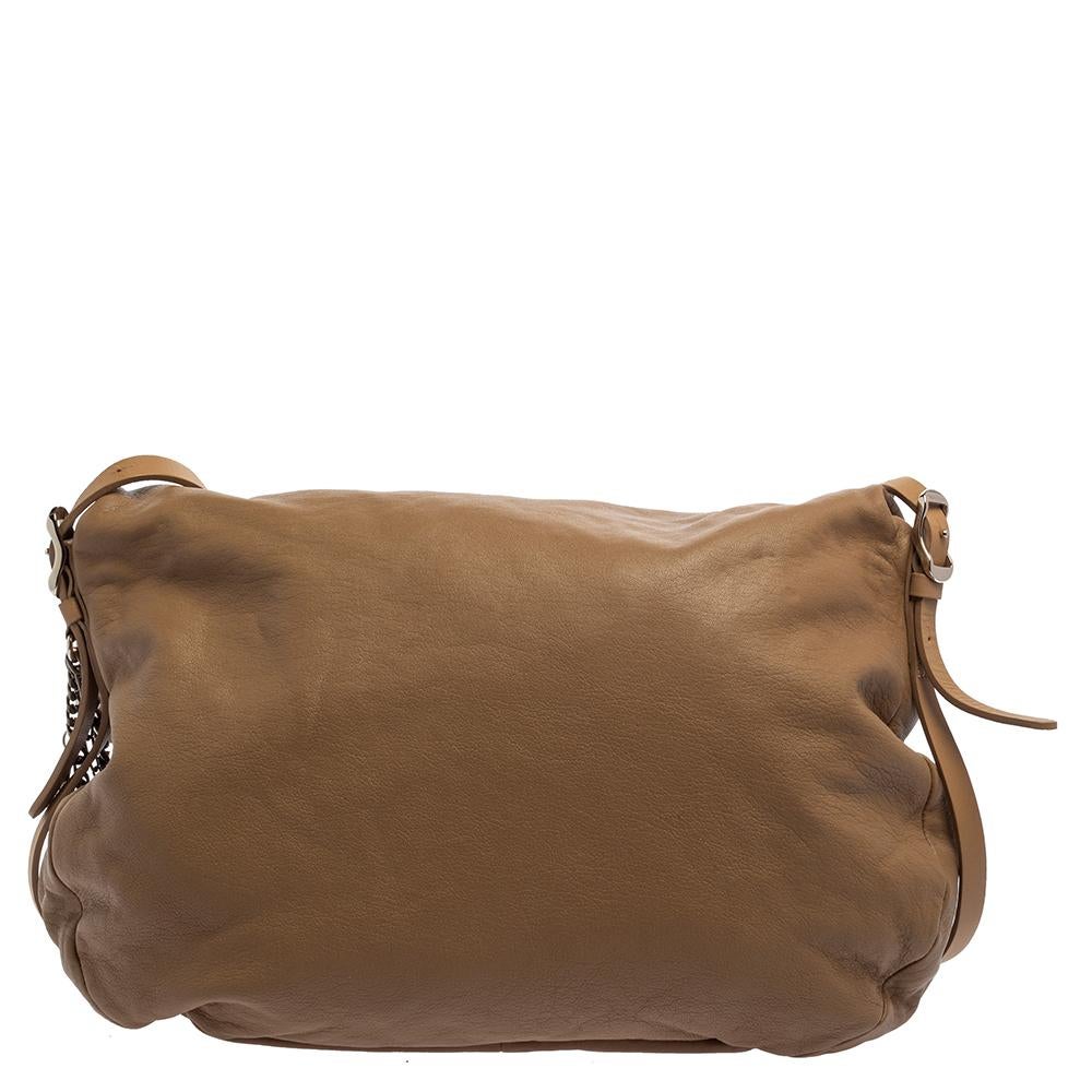 This hobo by Jimmy Choo will keep your hands free and your outfit stylish. It has been crafted from beige leather and designed with silver-tone chains that impart a chic look to it, It has a foldover silhouette and comes endowed with a spacious