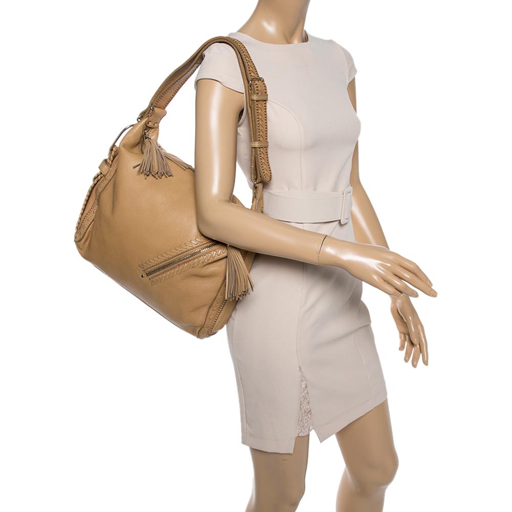 Crafted from beige-hued leather, this stylish Lily hobo from Jimmy Choo comes with a zip pocket to the front with a lovely tassel zipper pull. It features a shoulder strap and the zip-top closure opens to reveal an Alcantara-lined interior that is