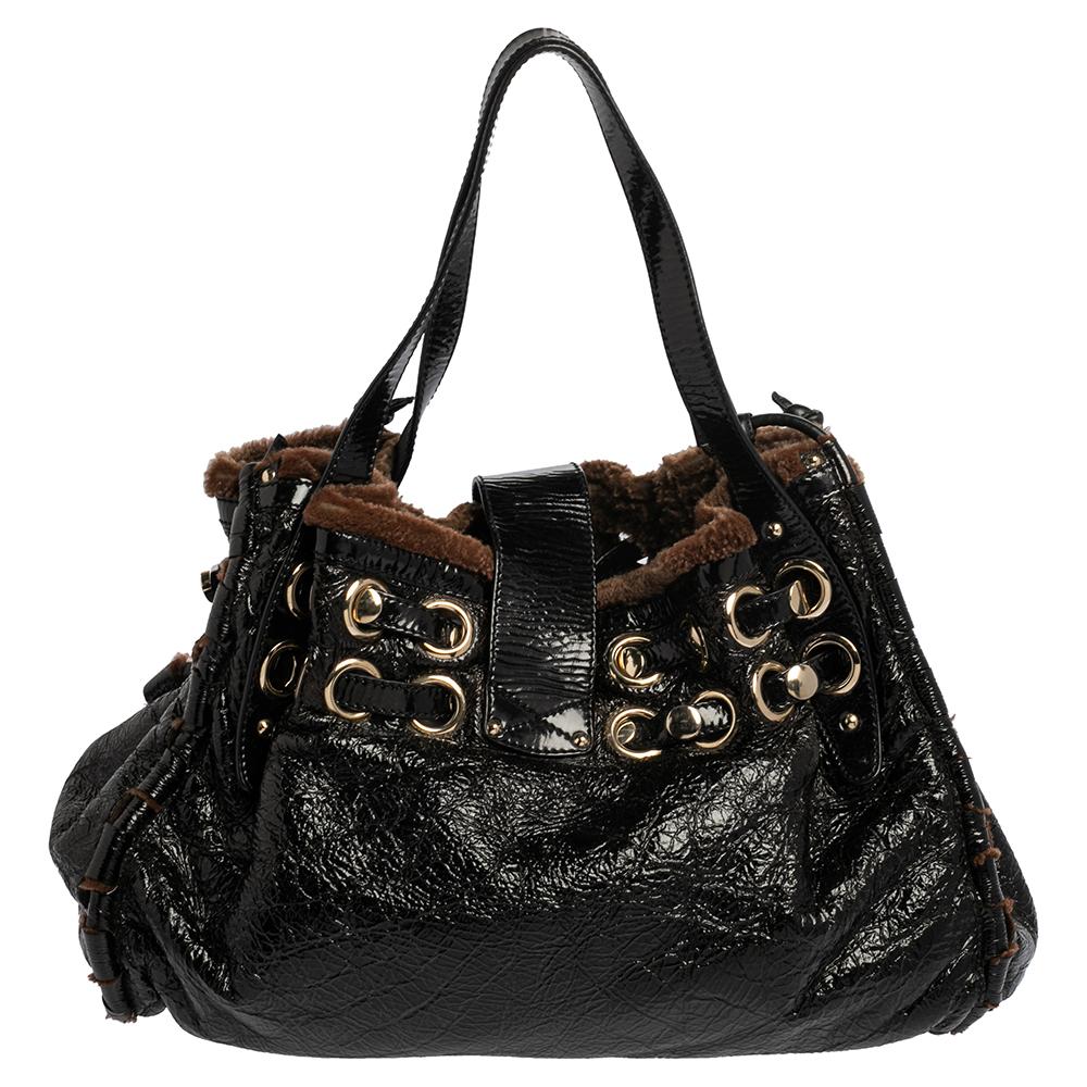 This gorgeous Jimmy Choo bag is crafted from black and brown leather and designed with shearling trims, dual belt detailing, and a front flip-lock. The piece is equipped with a well-sized interior and is complete with dual handles. A stylish bag