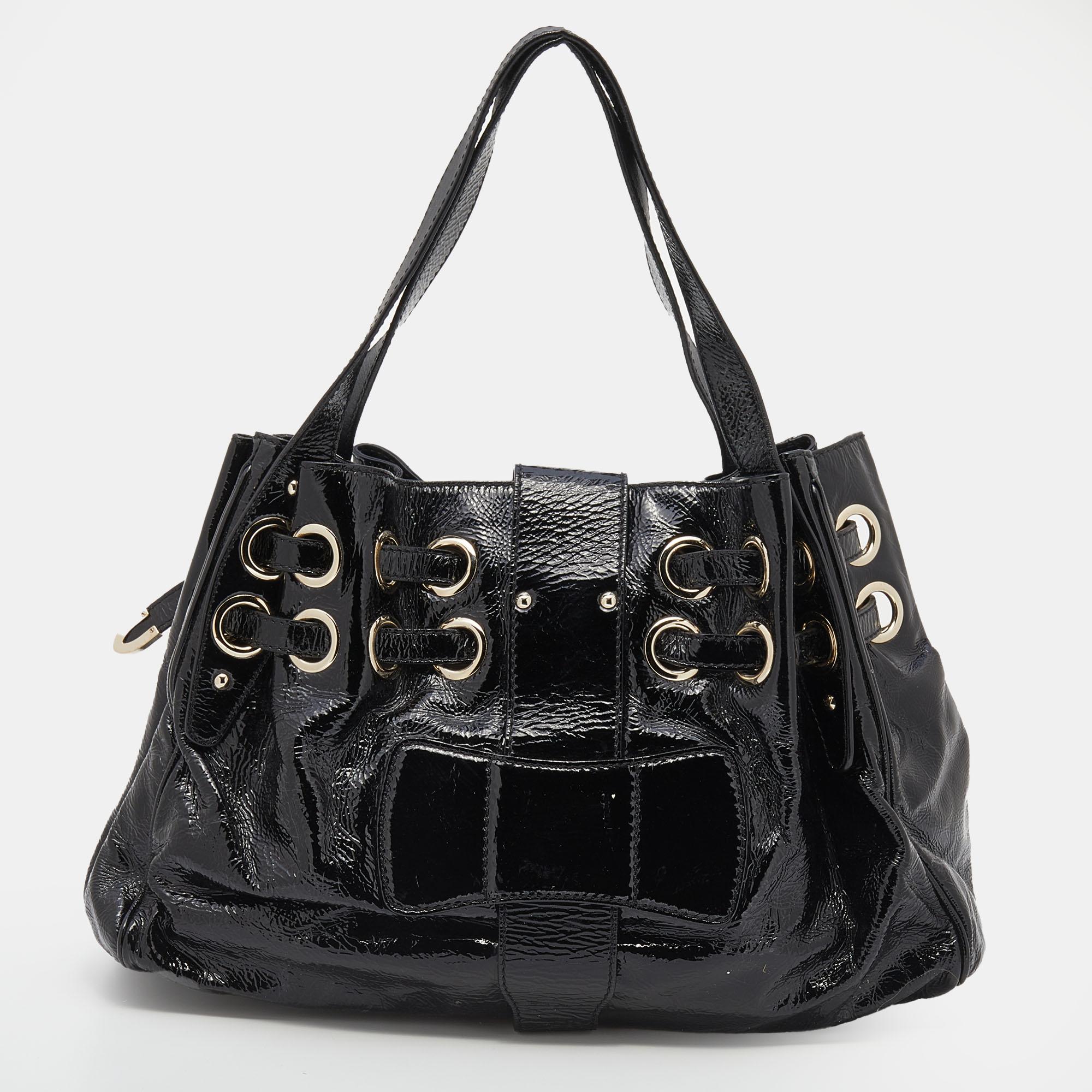 One of the most stunning creations from the House of Jimmy Choo is this Riki tote bag. It is made from black crinkled patent leather on the exterior. It features an Alcantara-lined interior and gold-tone hardware. The slightly-slouched silhouette of