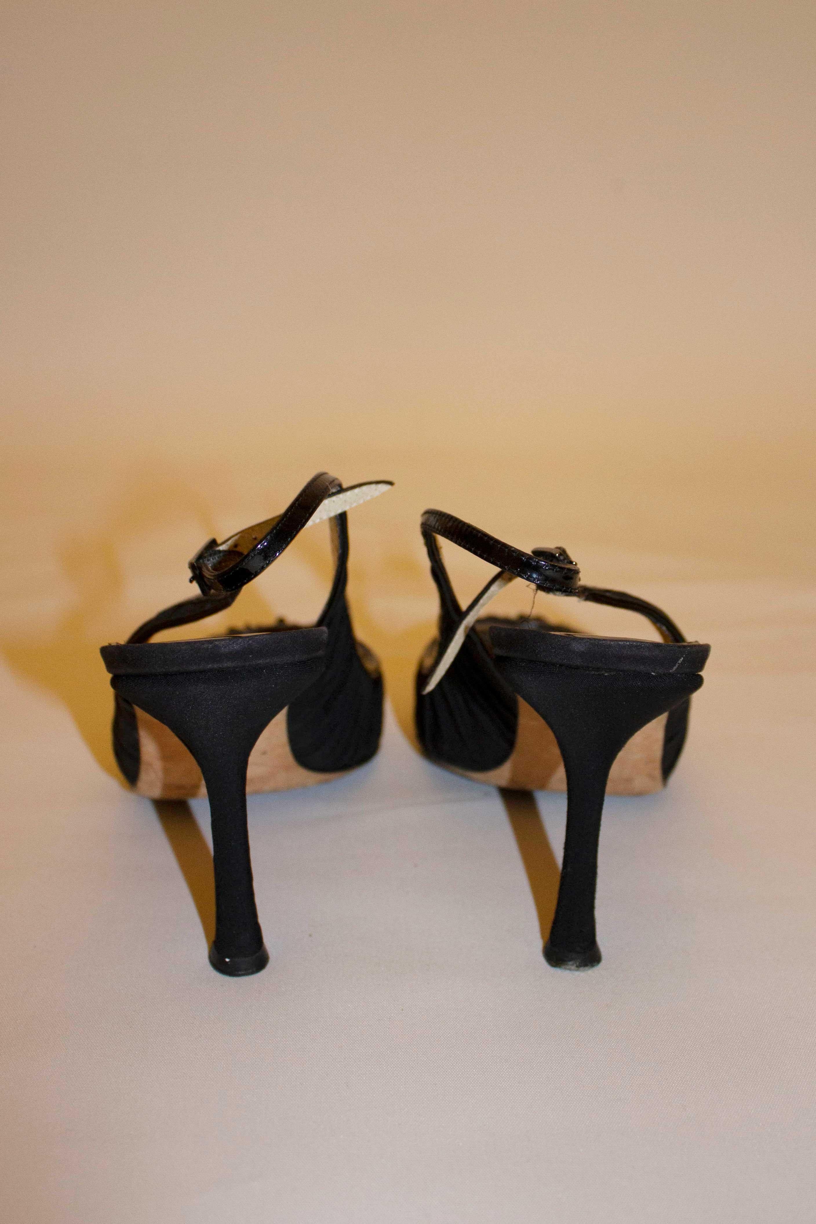 A chic pair of heels from Jimmy Choo. In black patent leather, and fabric, they have an attractive gathering over the foot with a patent leather trim.  Heel height 4'', size 40''