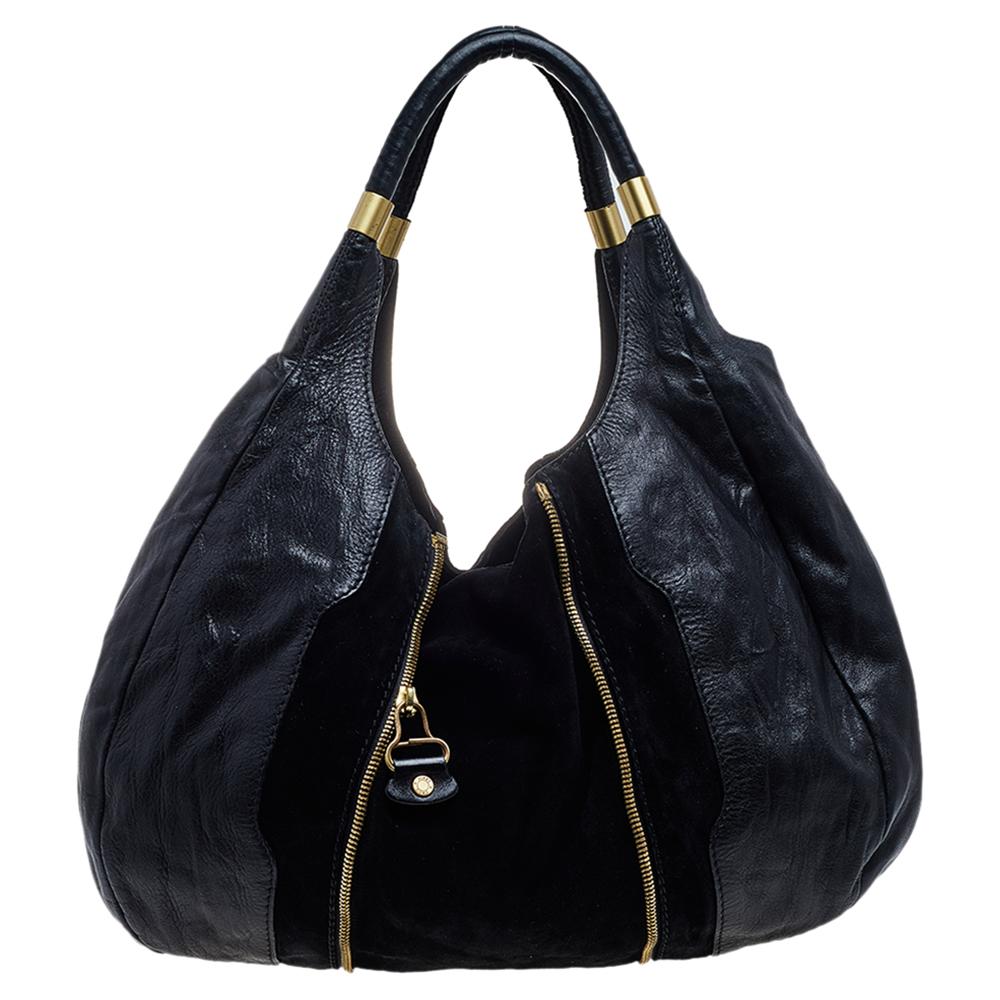 This Mona tote from the fashion label Jimmy Choo is uniquely designed. Crafted from leather and suede, this black bag features zippers and dual handles. The spacious bag opens to a suede-lined interior that has enough space for your essentials. It