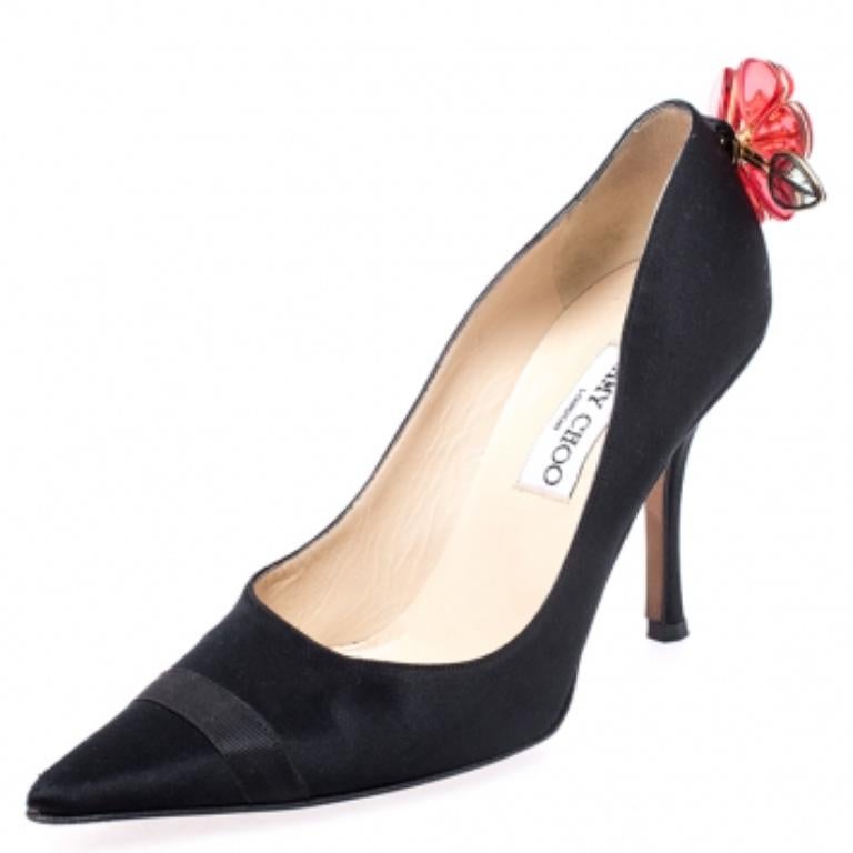 Dieses Paar Jimmy Choo Pumps ist ein stilvolles Statement und ein zeitloses Stück. Die aus feinem Satin gefertigten Pumps haben spitze Zehen, einen hohen Absatz und eine Blumenapplikation auf der Zunge.  Dezent und stilvoll, dieses Paar schwarzer