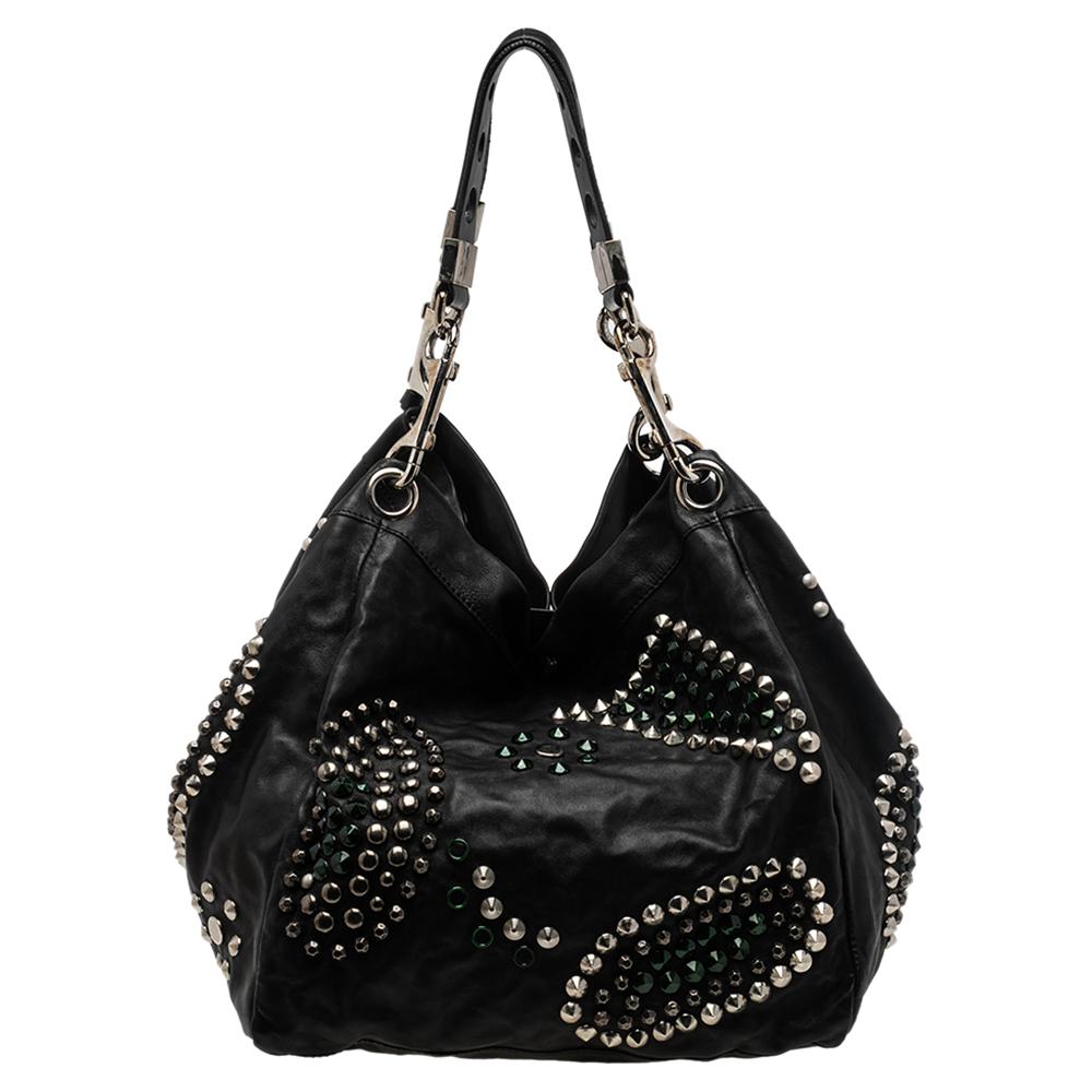 Jimmy Choo creations are revered for their edgy touch, great quality, and precise craftsmanship. This tote bag is a prime example. The tote has been crafted from leather and carries a classic shade of black. It has stud detailing all-over, dual