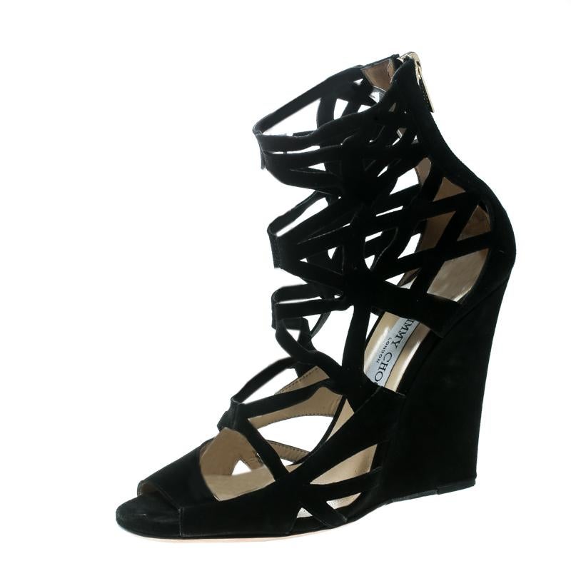 Abbiamo il cuore in mano per questi sandali a gabbia di Jimmy Choo. Questo paio nero è stato realizzato in pelle scamosciata e presenta tagli al laser, cerniere posteriori e tacchi a zeppa. Porta fuori questo numero e fai la figura della diva dello