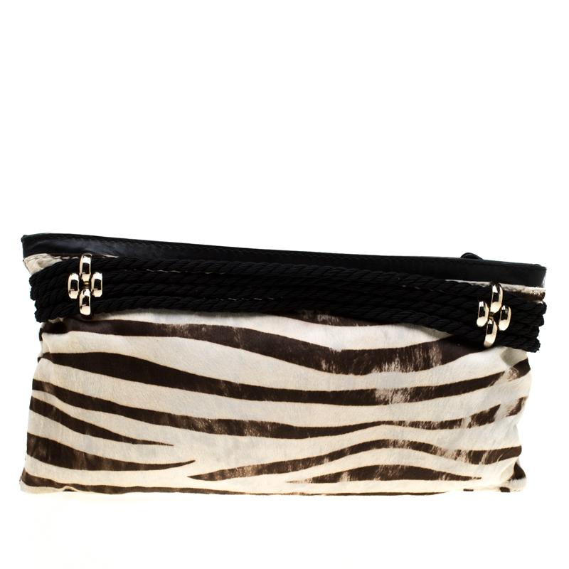 Chic and very stylish, this clutch from Jimmy Choo deserves all your attention! The black and white clutch is crafted from calfhair and features a zebra print. It has been styled with a gold-tone buckle strap on the front and opens to an Alcantara