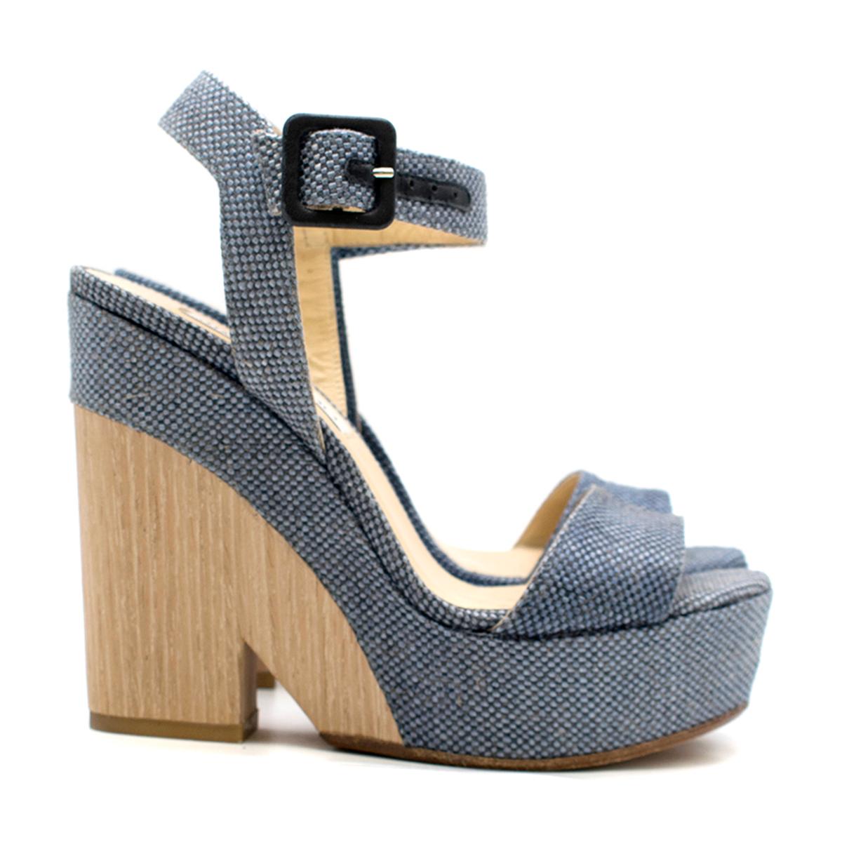 Jimmy Choo Blue Fine Raffia Nico 125 Wedge

- Blue woven 
- Fine raffia upper
- Leather trim
- Ankle strap buckle fastening
- Open toe
- Wood-effect wedge
- Nude leather lining with logo embossed
- This item comes with the original shoe box.

Please