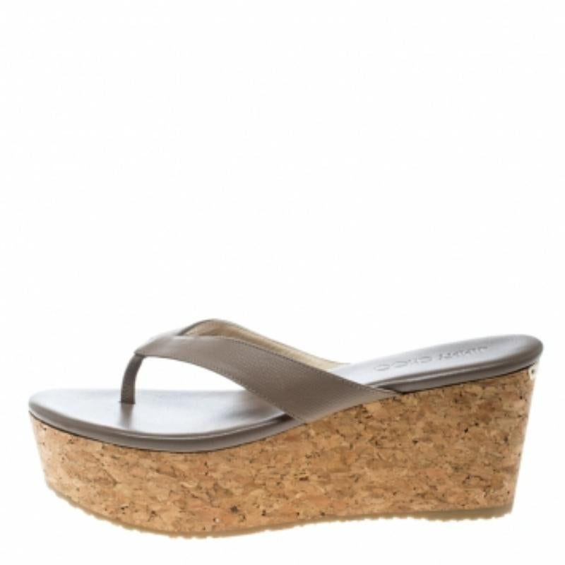 These beige Paque sandals from Jimmy Choo are crafted from embossed leather and feature a thong design. They come equipped with comfortable leather lined insoles and 8 cm cork wedge heels with a gold-tone brand plaque at the back.