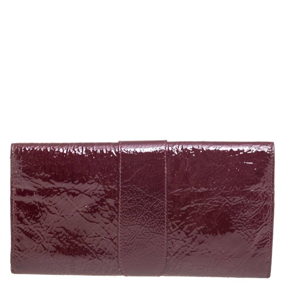 The Jimmy Choo Reese Clutch is both practical and appealing. Crafted from burgundy patent leather, this clutch is presented in a simple silhouette. The front flap with a gleaming logo plaque opens to a nylon-leather interior housing card