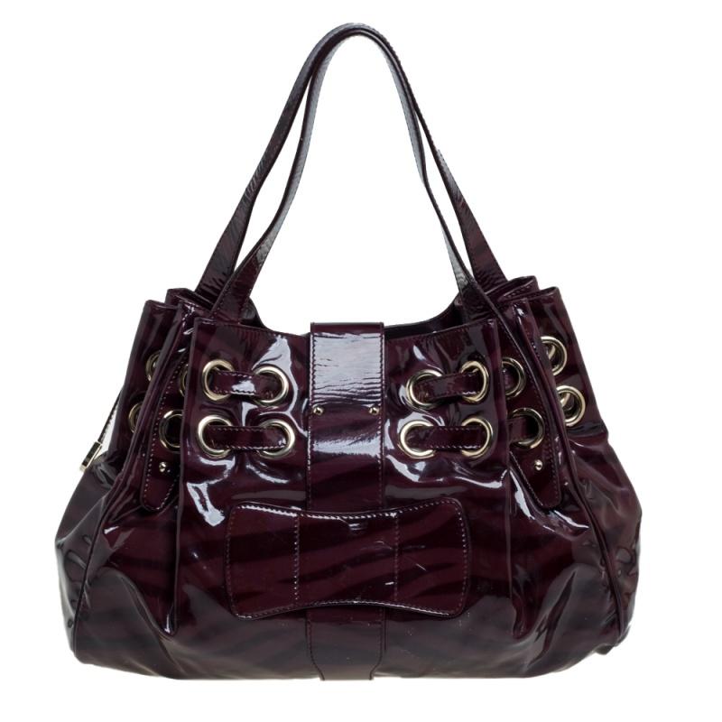 The popular Ramona is another perfectly designed and practical handbag from Jimmy Choo. Crafted from zebra printed burgundy patent leather, it is accented with double drawstrings and large grommets, a logo-engraved flip lock, and dual shoulder