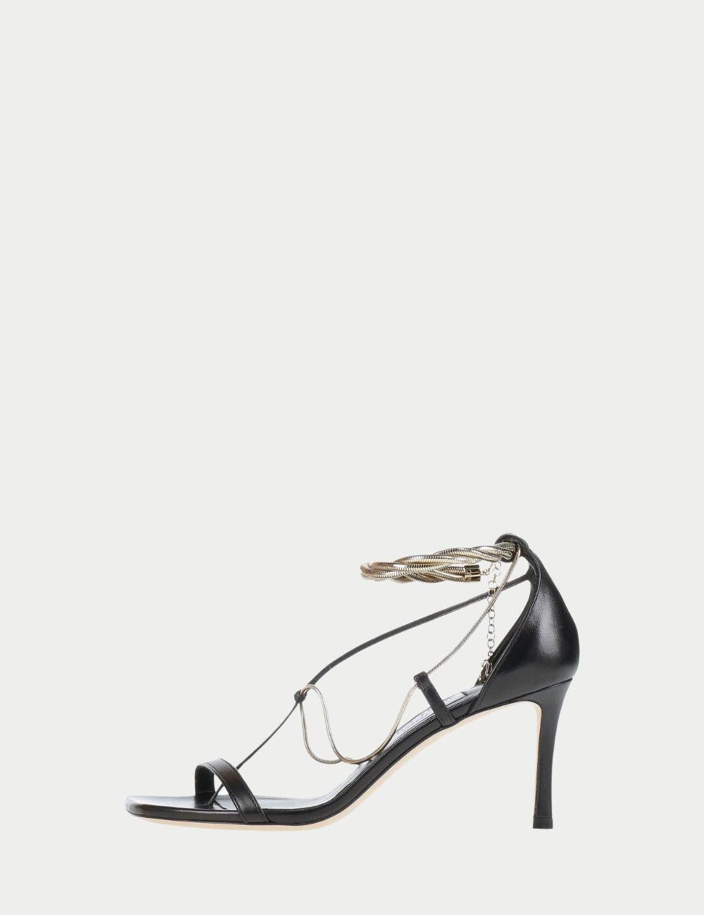 Jimmy Choo Black Strappy Ankle-Tie Heels - Gold Chain Detail

Entrez dans l'élégance avec ces remarquables sandales à talons hauts noires de Jimmy Choo. Dotés d'un bout carré élégant, d'une bride frontale minimaliste et d'attaches de cheville en