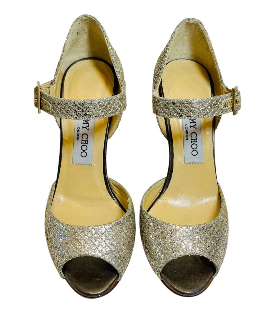 Jimmy Choo Glitter Mary Jane Sandals
Champagne gold glitter pumps designed with peep toe and 'Jimmy Choo' engraved aged gold buckle.
Featuring stiletto heel and leather lining and soles.
Size – 35.5
Condition – Good (General signs of wear, wear to