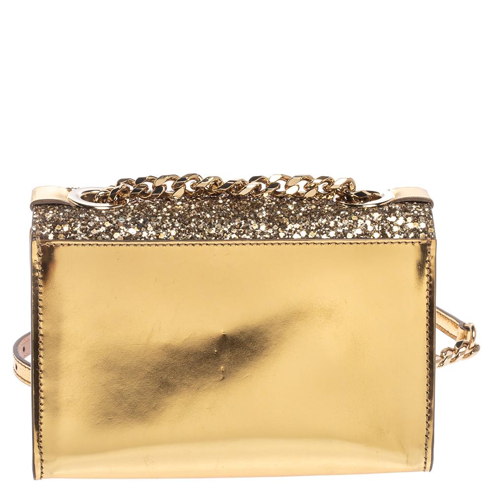 This stunning Rebel crossbody bag from Jimmy Choo is high on appeal and style. The bag is crafted from glitter and patent leather and designed with a flap that has a flip lock and leads way to a suede-lined interior. The gold bag is held by a