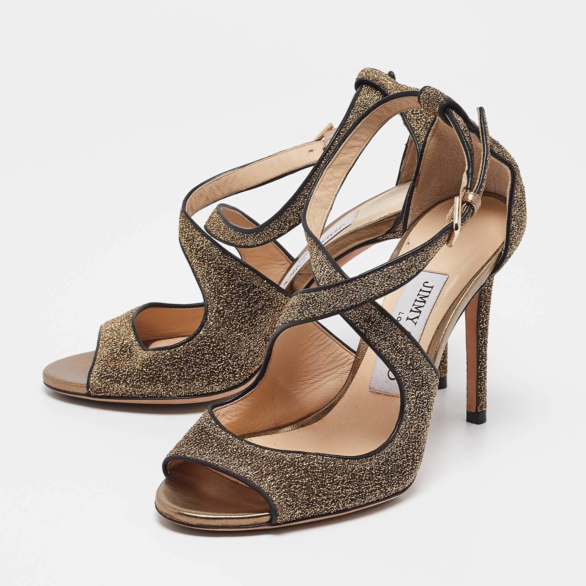 Complétez votre look de nuit avec ces superbes sandales Jimmy Choo Emily. Il se compose d'un corps en cuir doré et en tissu lurex avec des lanières qui encadrent joliment les pieds. Elles sont montées sur des talons élégants et fermées par une